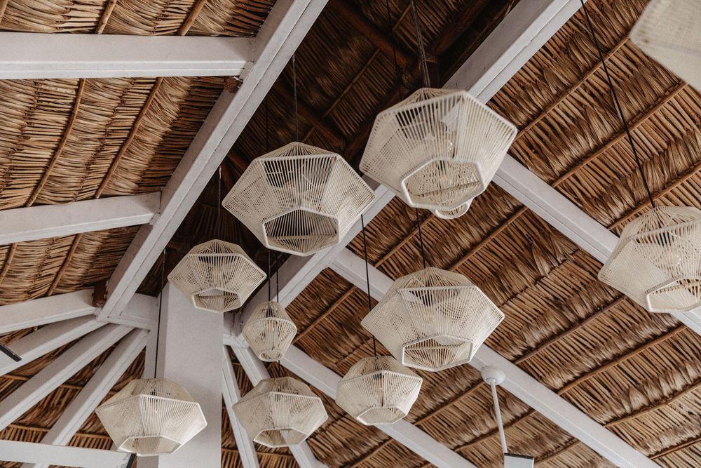 Rustic bamboo roof with white pendant lights hanging in a tropical beach style setting.