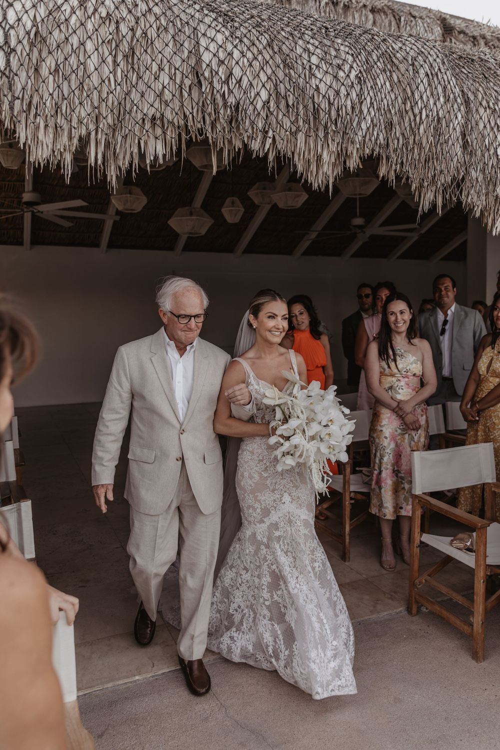 A sequence of wedding photos showing a couple walking under a thatched palm roof structure during a ceremony.