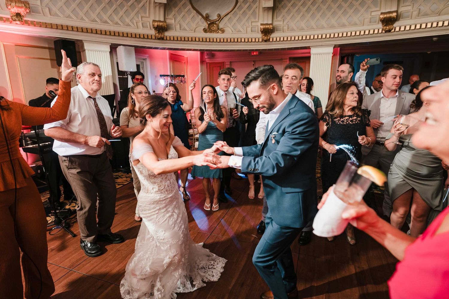 Bride and groom dancing energetically surrounded by guests on a packed dance floor during a lively wedding reception at the Lenox Hotel Bost
