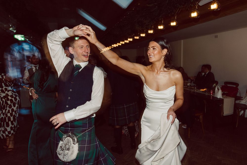 Joyful couple dancing together at their wedding reception in formal attire.