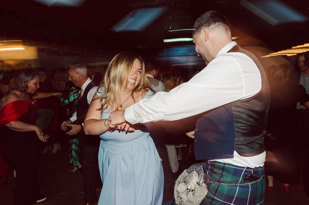 People dancing together in a dark room during what appears to be a social dance event or celebration.