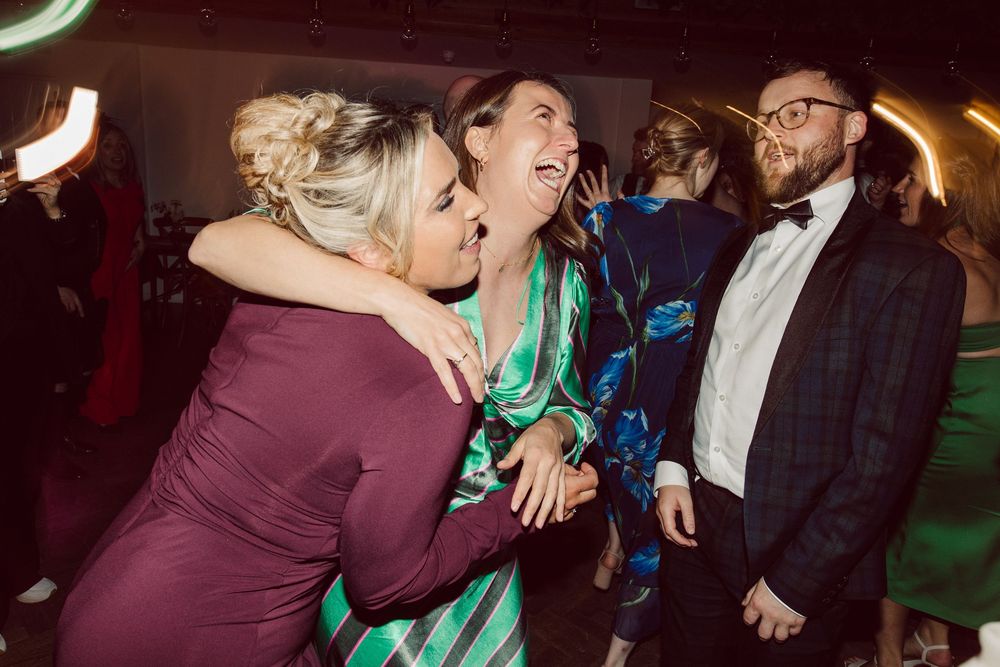 People dancing and celebrating at a lively party with colorful lighting and festive atmosphere.