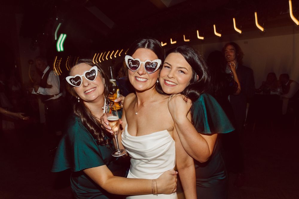Group of friends enjoying a party together with drinks and laughter in a dimly lit venue.