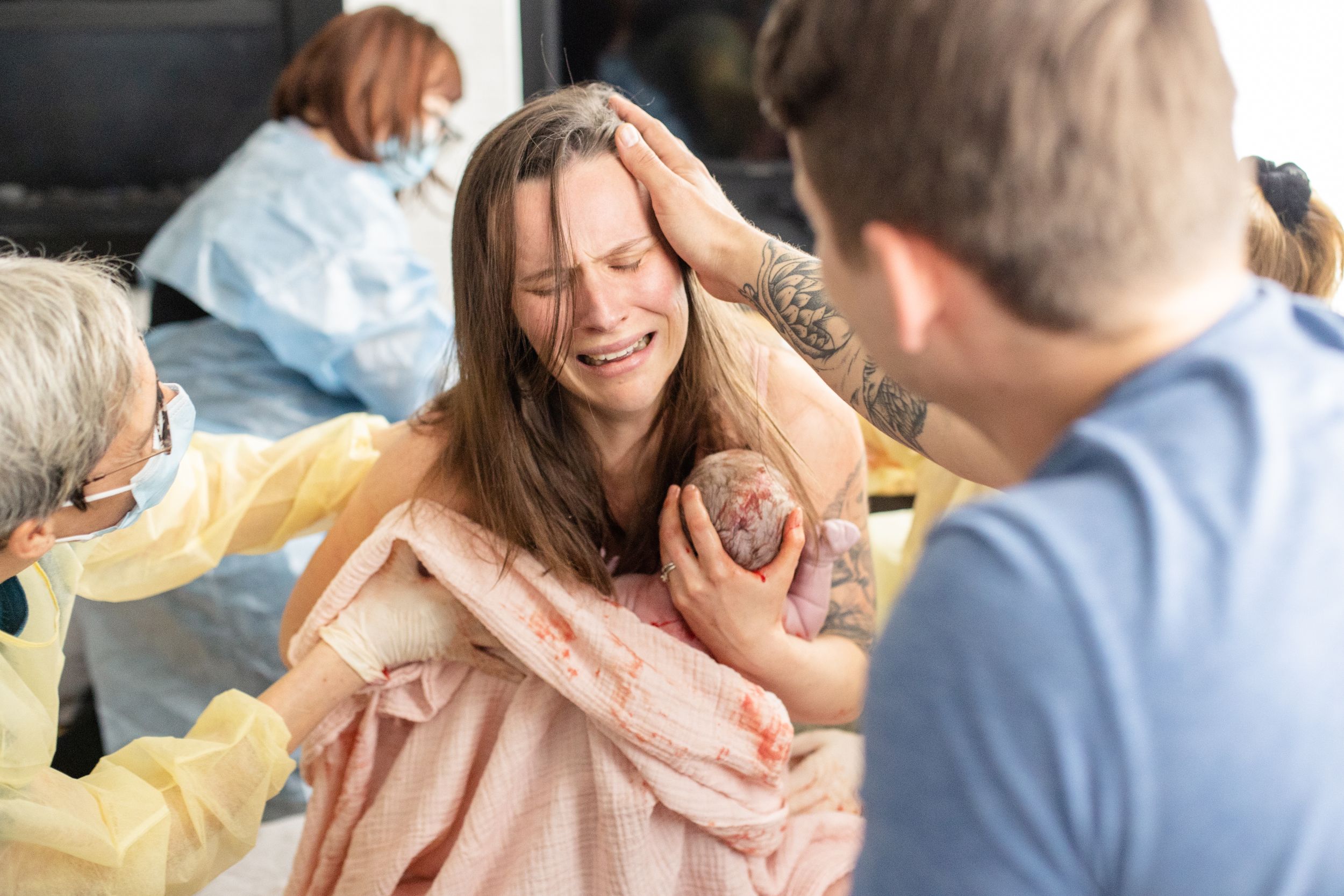 Mom is holding newborn baby boy immediately after birth. Mom looks relieved and happy.