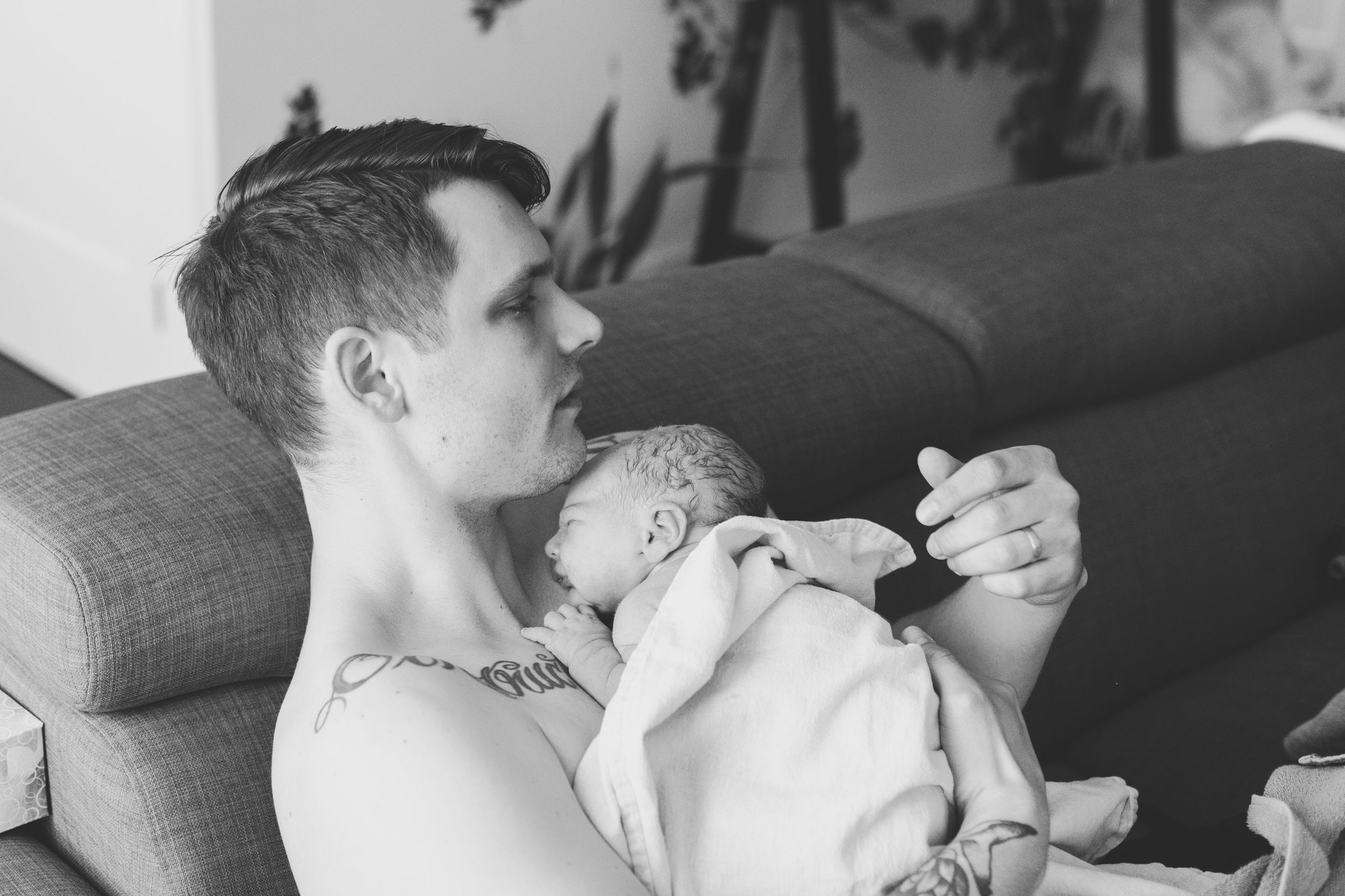 Newborn baby boy doing skin to skin with dad. Dad is sitting on couch.