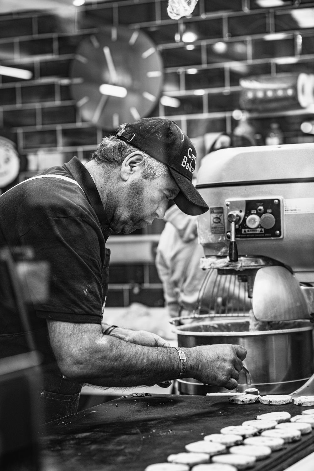 Black and white picture of a man placing welsh cakes onto a bakestone to cook. Candid corporate photography in Cardiff, South Wales