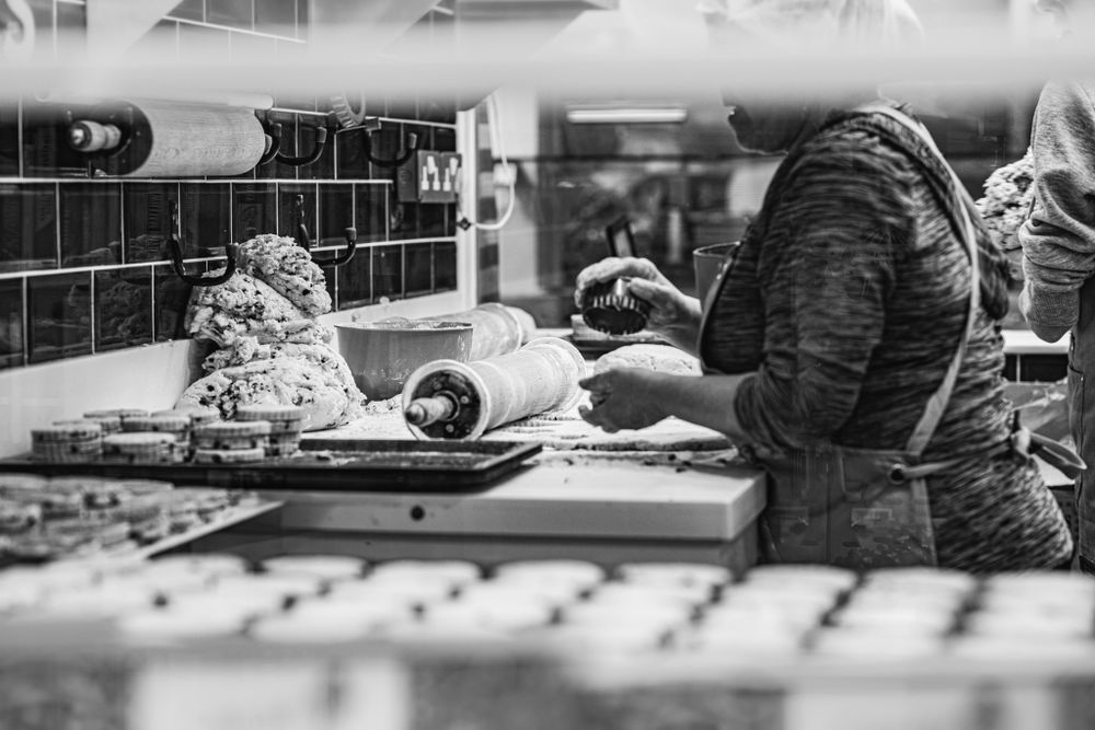Black and white picture of a woman mixing dough to make welsh cakes at Cardiff bakestones. Corporate photography in Cardiff, South Wales
