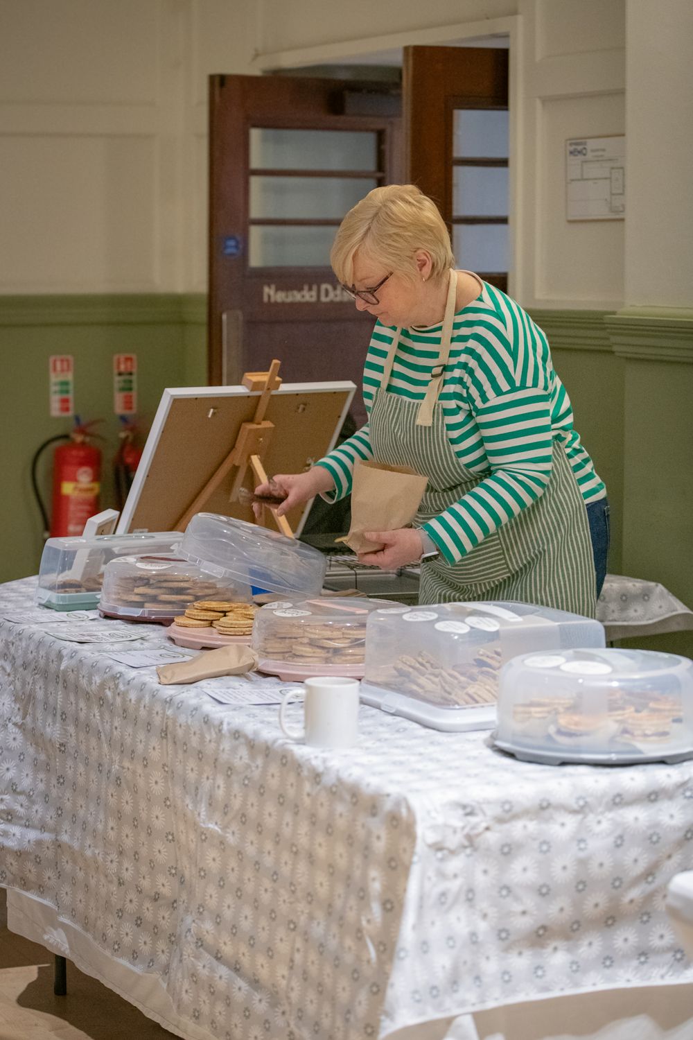 Lady in a green and cream stripped top serving welsh cakes from her stall. Shot by K Lewis Photography