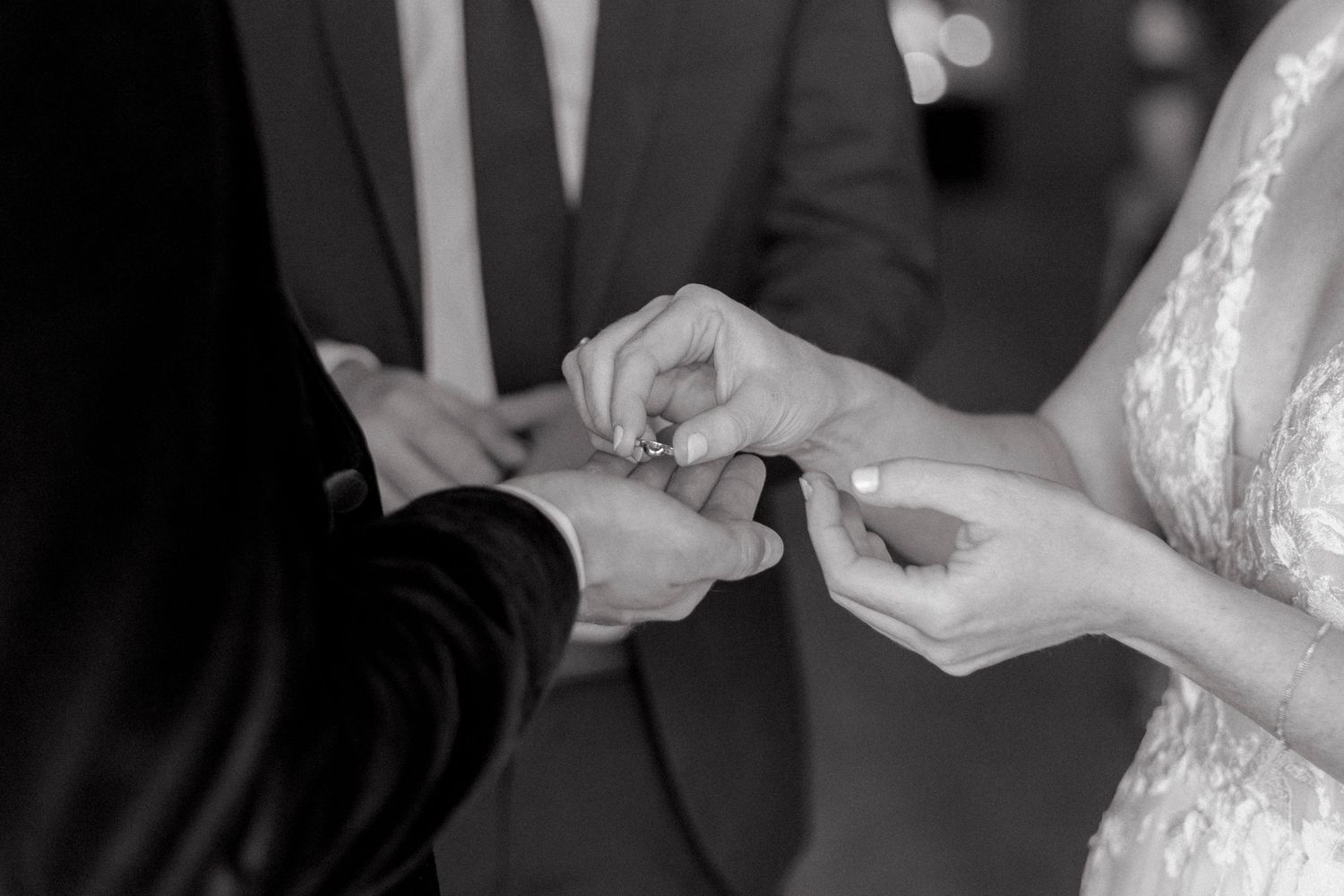 A close-up shot of wedding rings being exchanged during a ceremony. Black and white wedding photography.