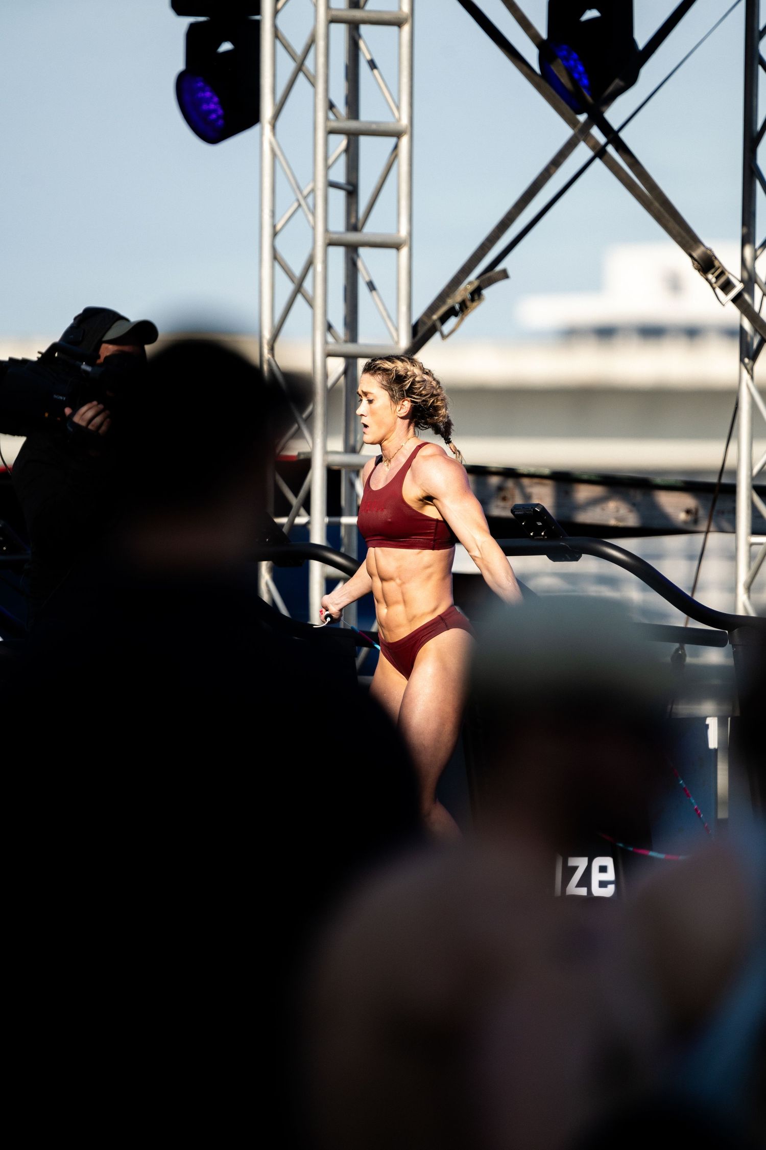 An athlete performs on stage during a fitness competition with stage lighting and cameras.