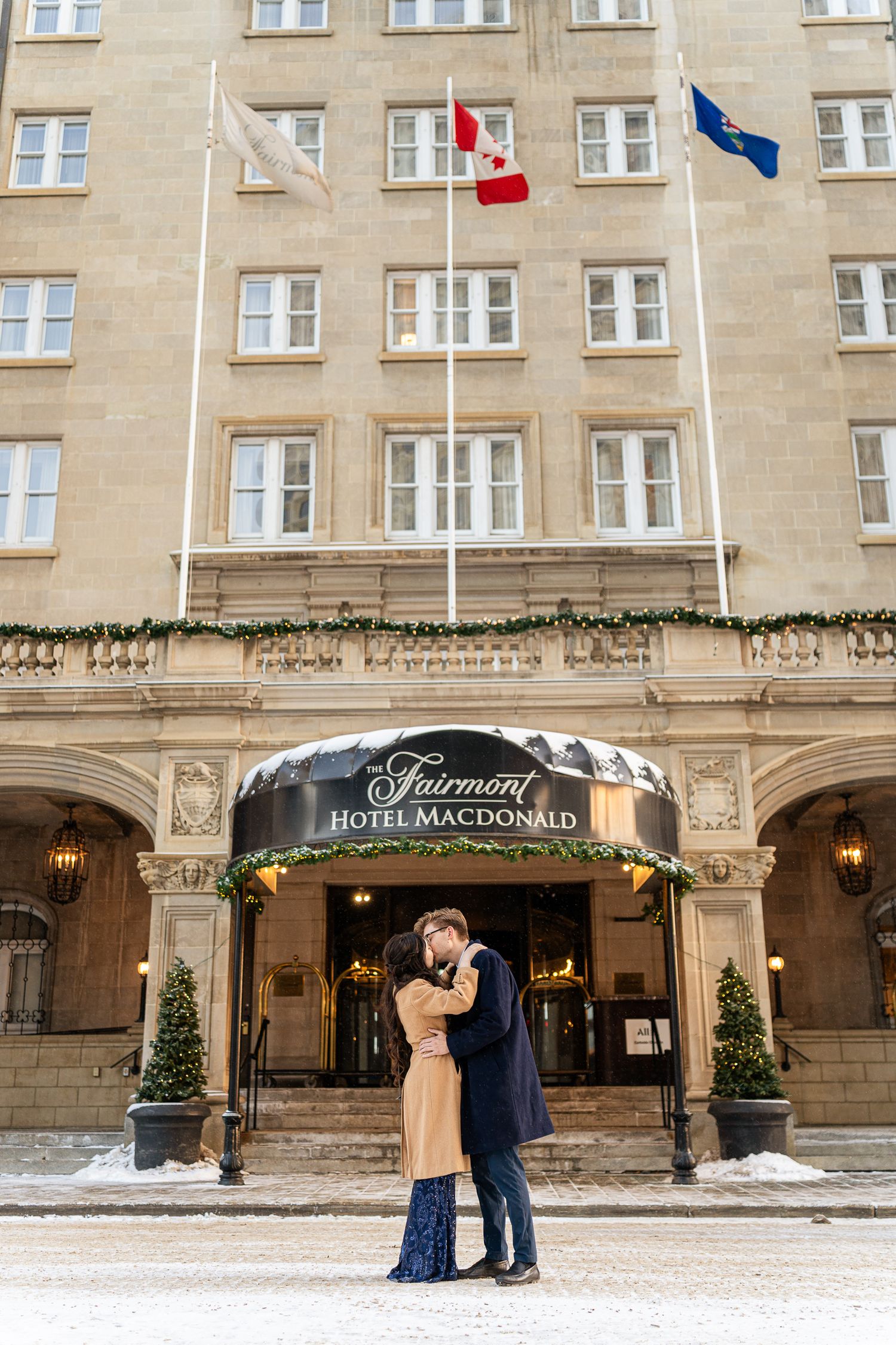 A romantic winter scene outside the historic Fairmont Hotel Macdonald with snow on the ground and holiday decorations.