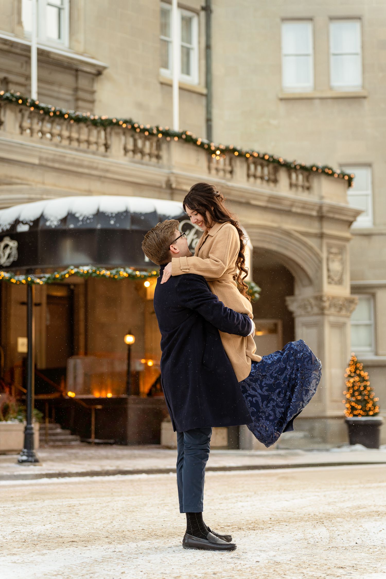 A romantic winter scene outside a decorated building with holiday garland and twinkling lights.