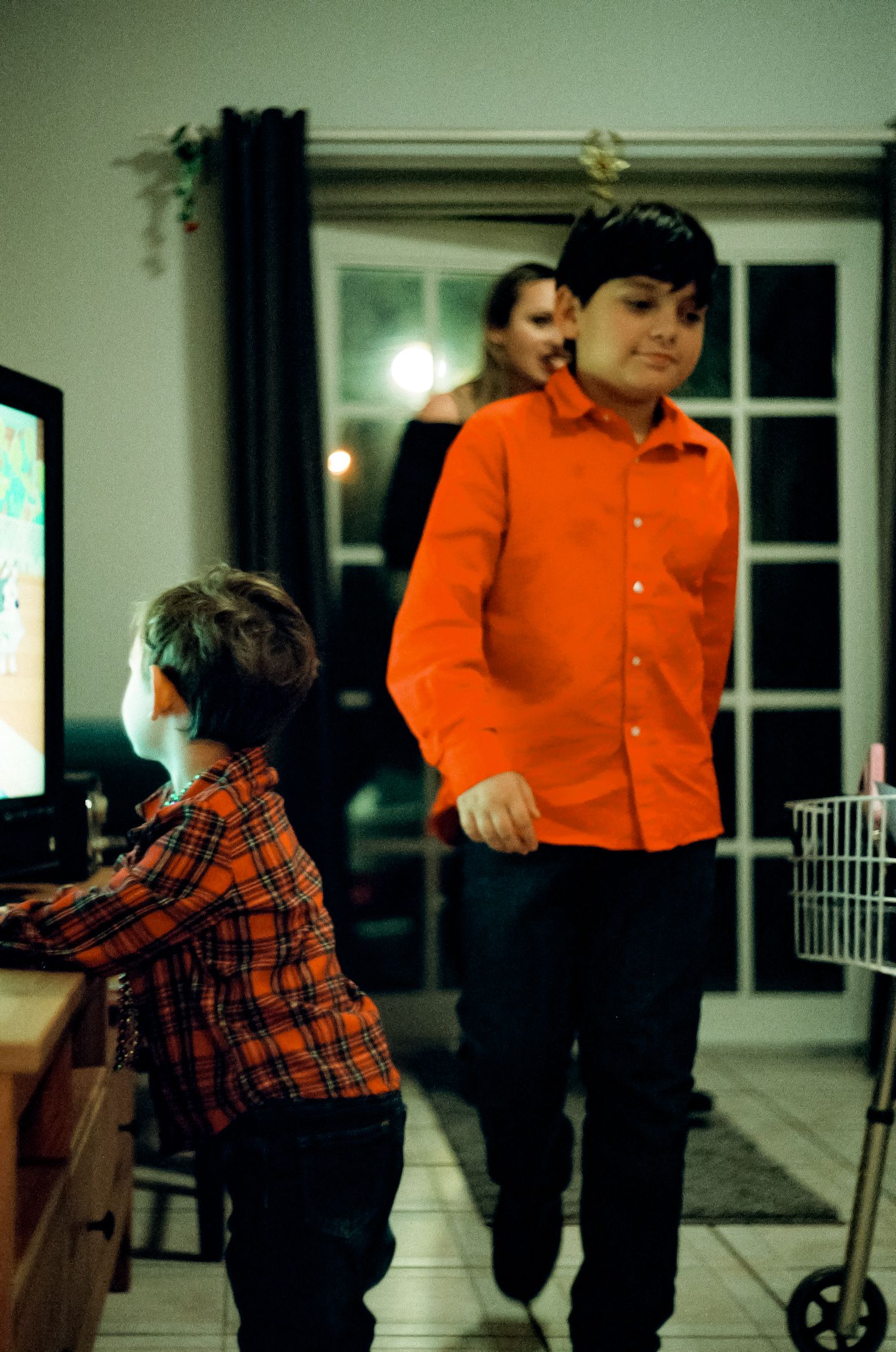 Two people standing by a TV console in a living room at night.