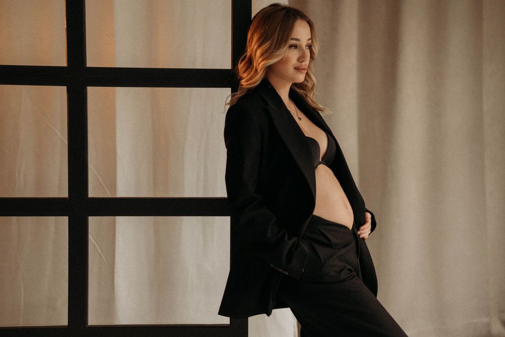 Elegant portrait series in black attire against light curtained background.