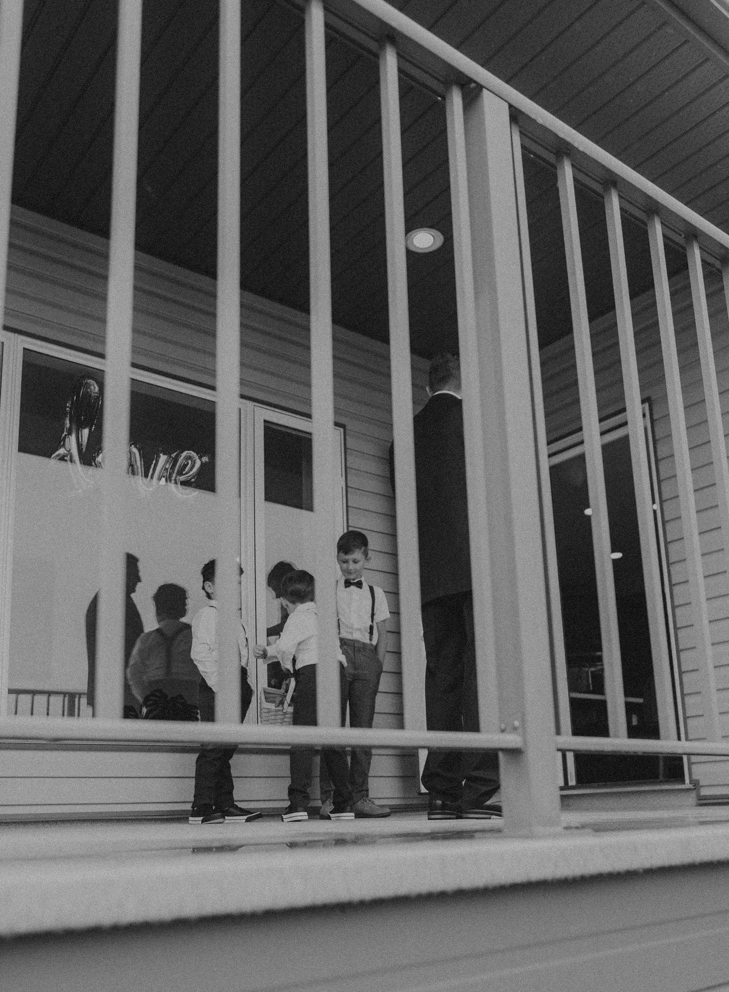 Vintage black and white photo of a group on a porch with vertical railings.
