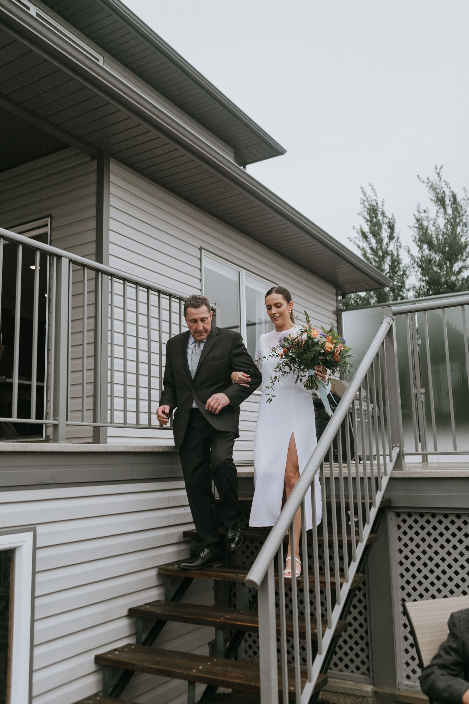Wedding party descending outdoor stairs of a white building.