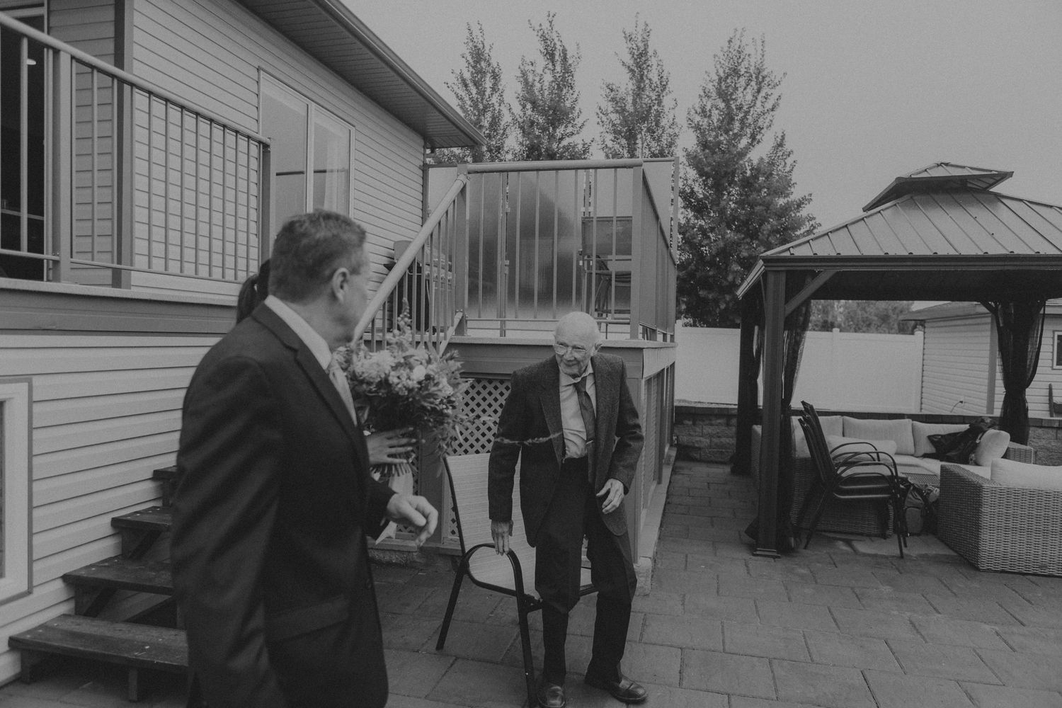 A black and white image of figures conversing on an outdoor patio with gazebo.