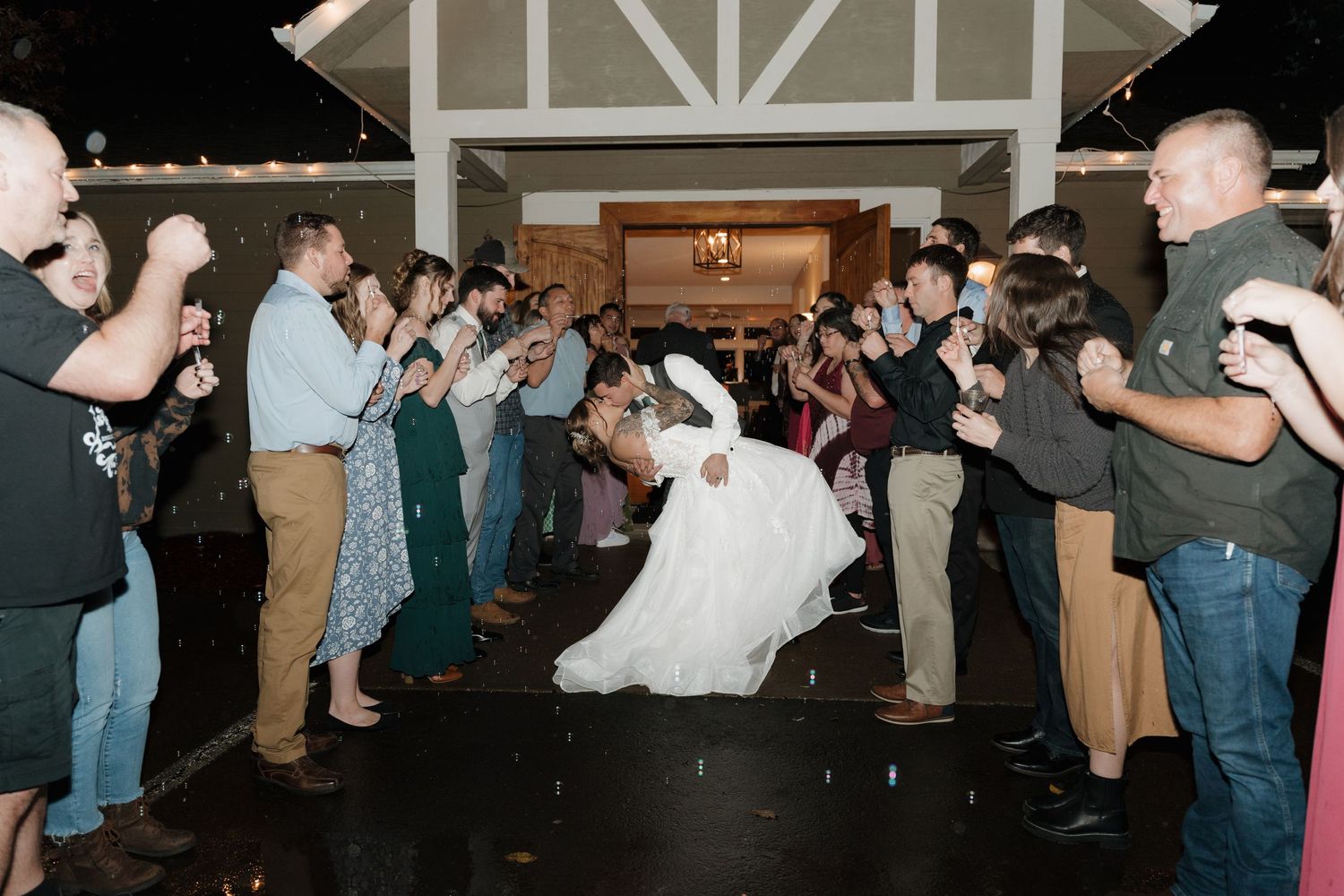 Wedding guests form a sparkler exit tunnel as newlyweds share a romantic dip during their reception sendoff.