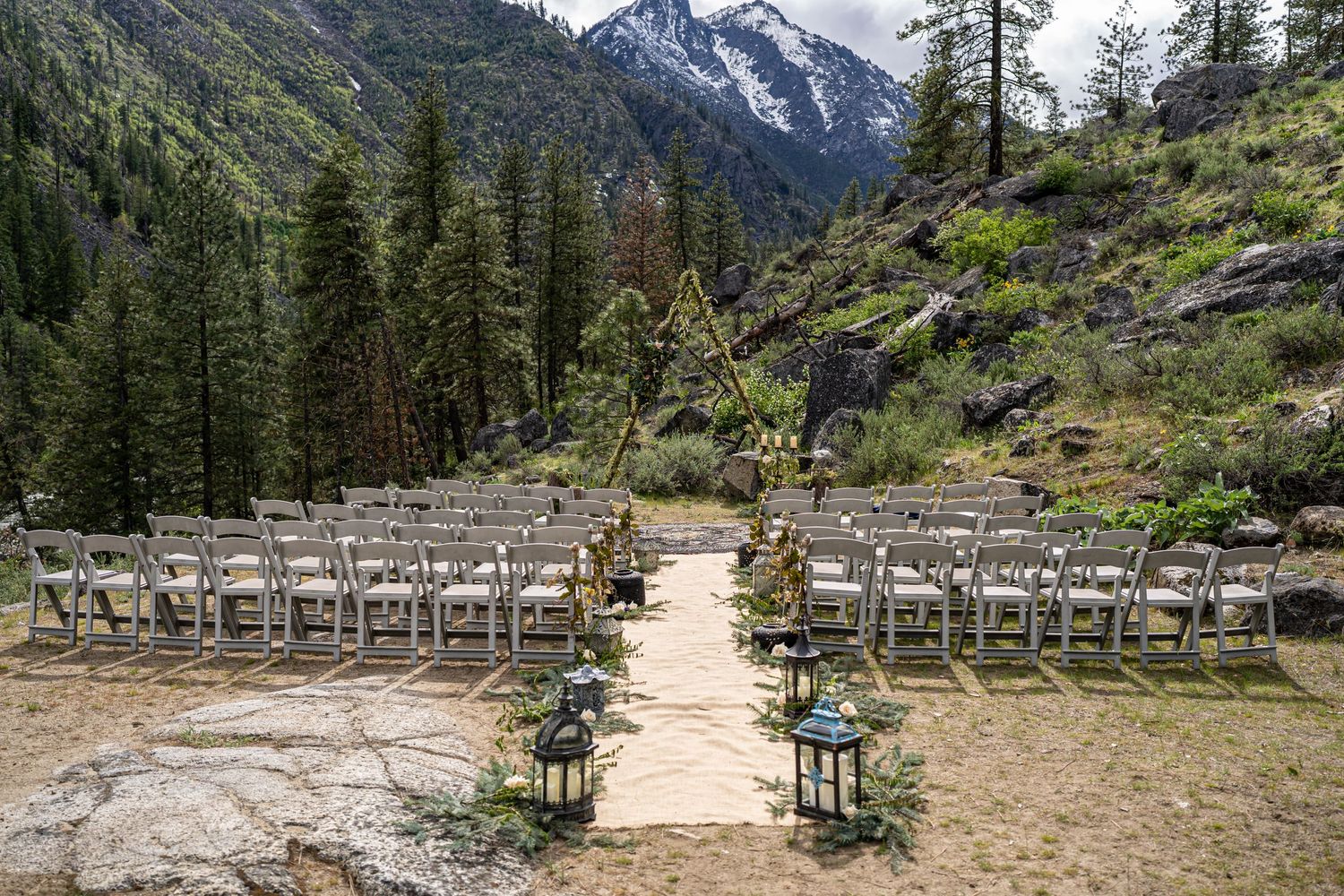 Empty wedding ceremony setup with white chairs and mountain vista in the background.
