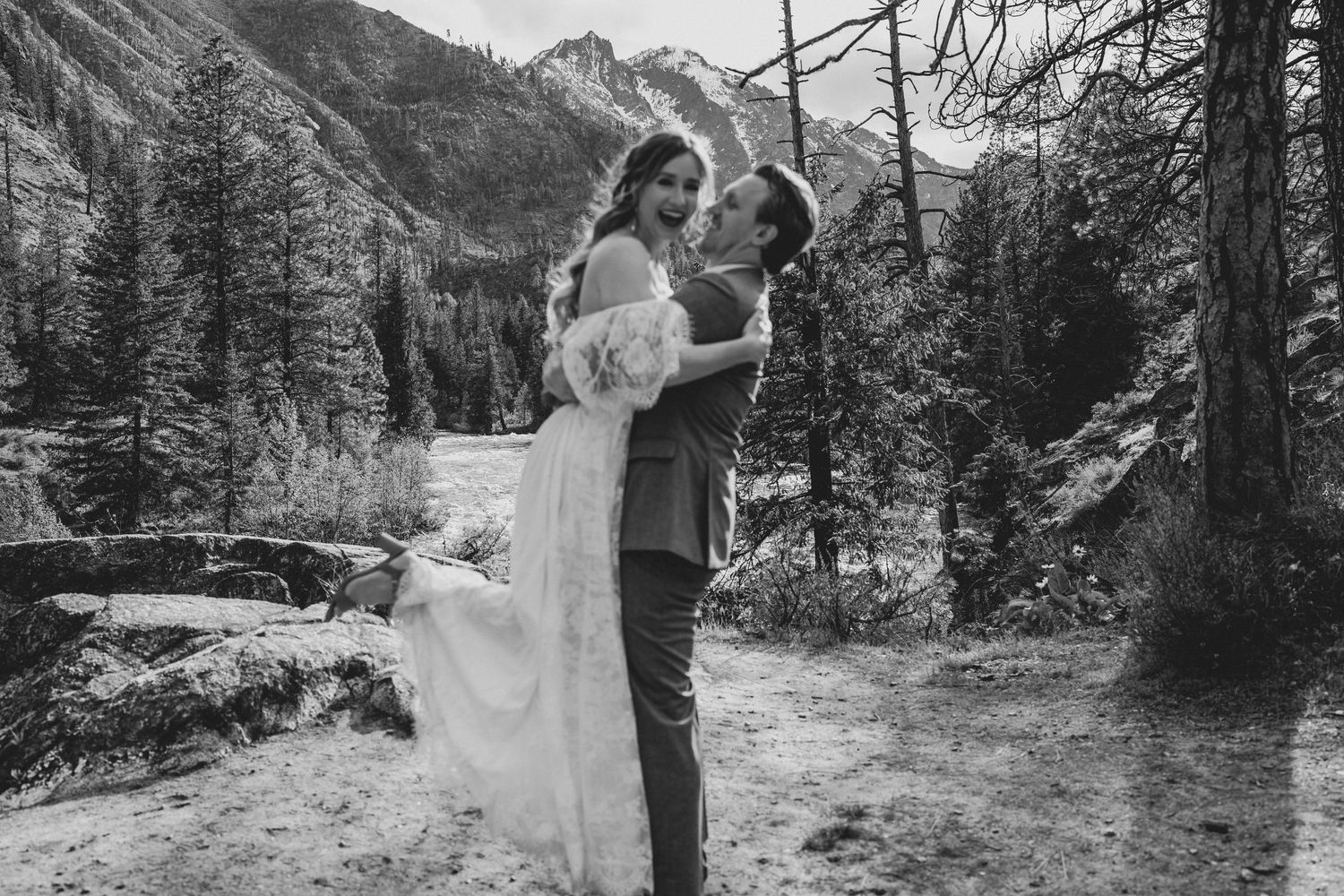 Black and white romantic portrait of newlyweds in a scenic mountain forest setting.