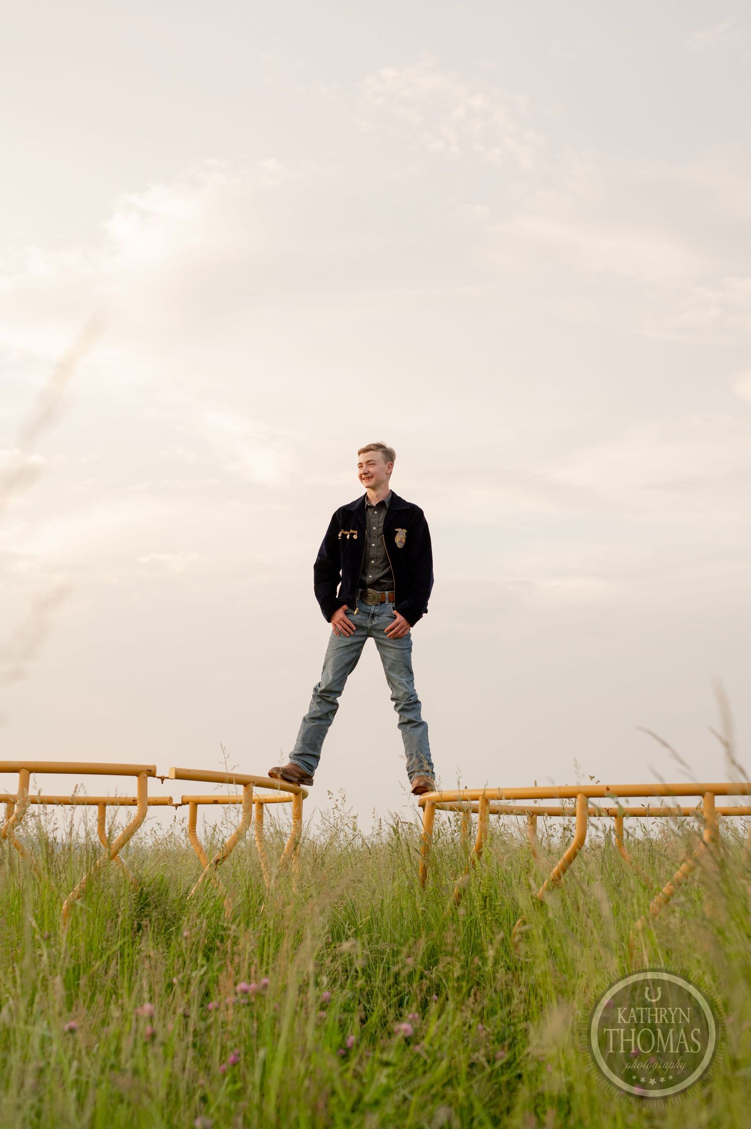 Low angle view of student on wooden fence with golden field and soft sky.