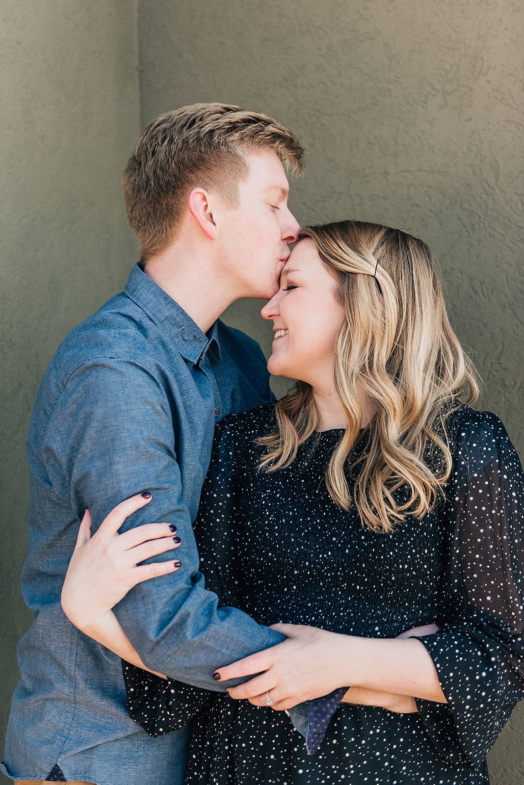 Intimate moment shared between couple against neutral wall background.