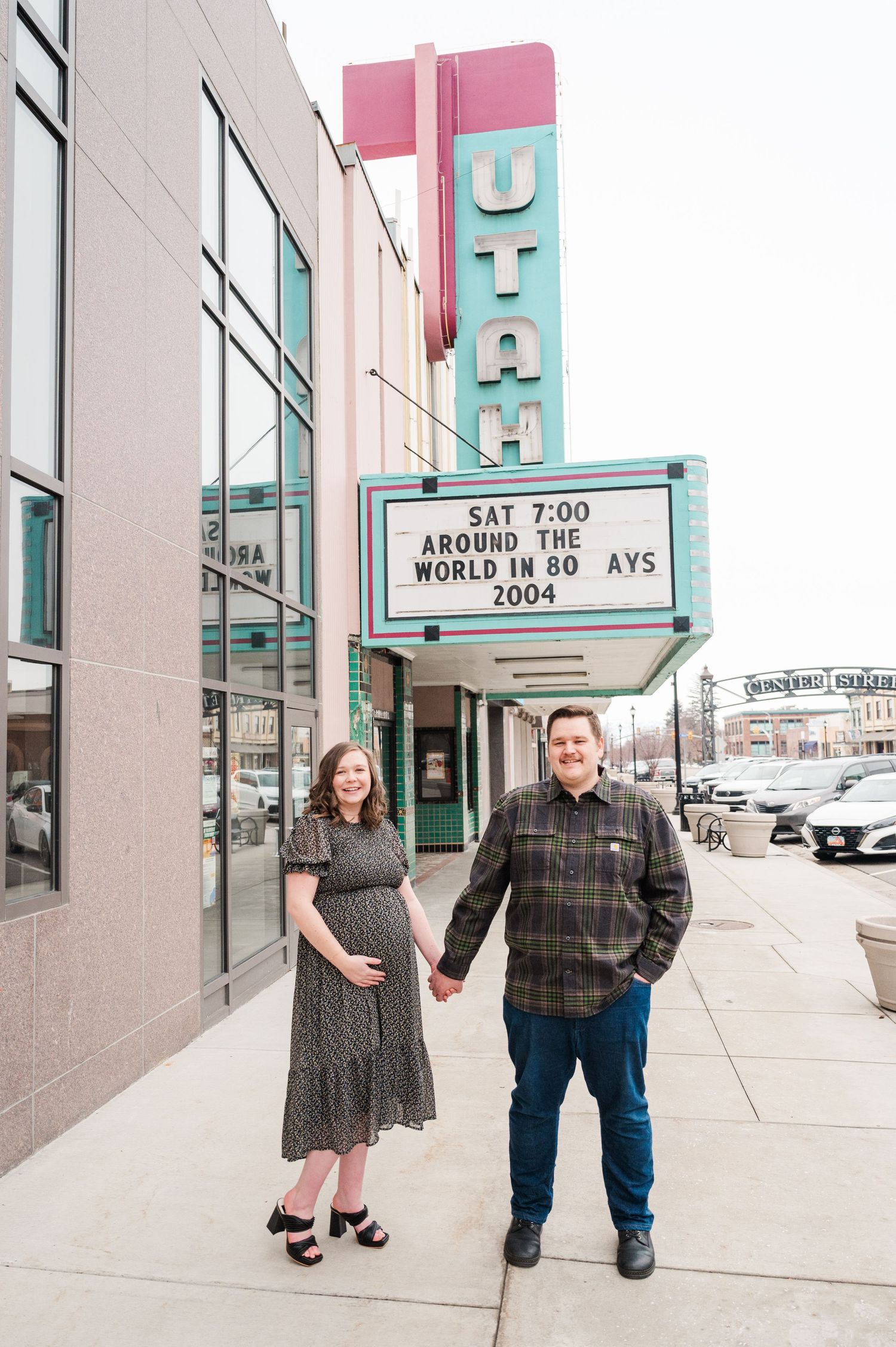 Couple posing in front of Utah theater marquee on city sidewalk.
