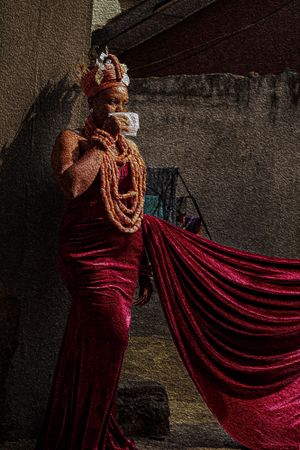 Photography Oil painting of a Benin Bride in burgundy velvet gown with traditional African crown covering a face in a cultural Benin way.
