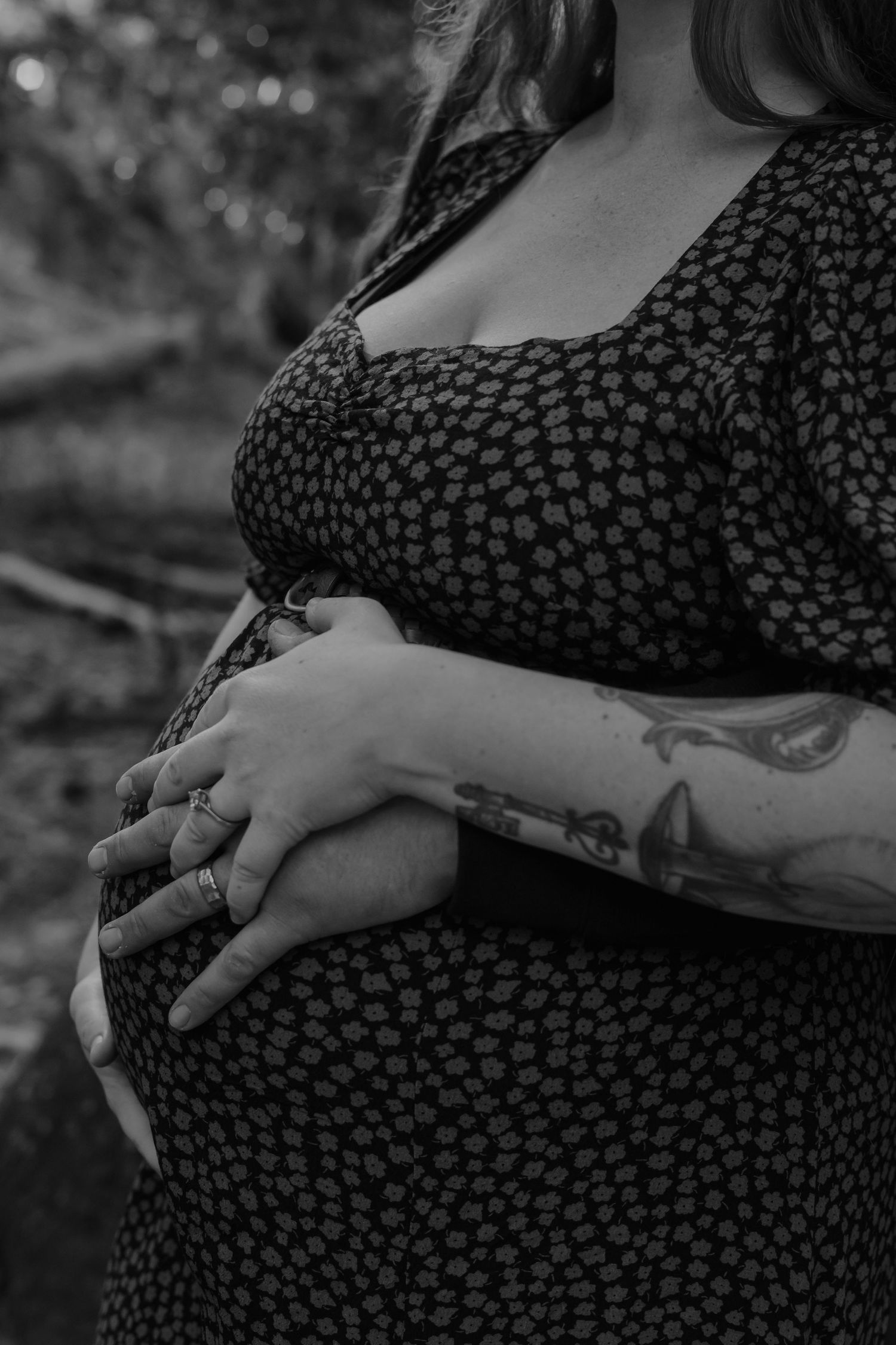 Close-up of tattooed hands resting on a polka dot maternity dress.