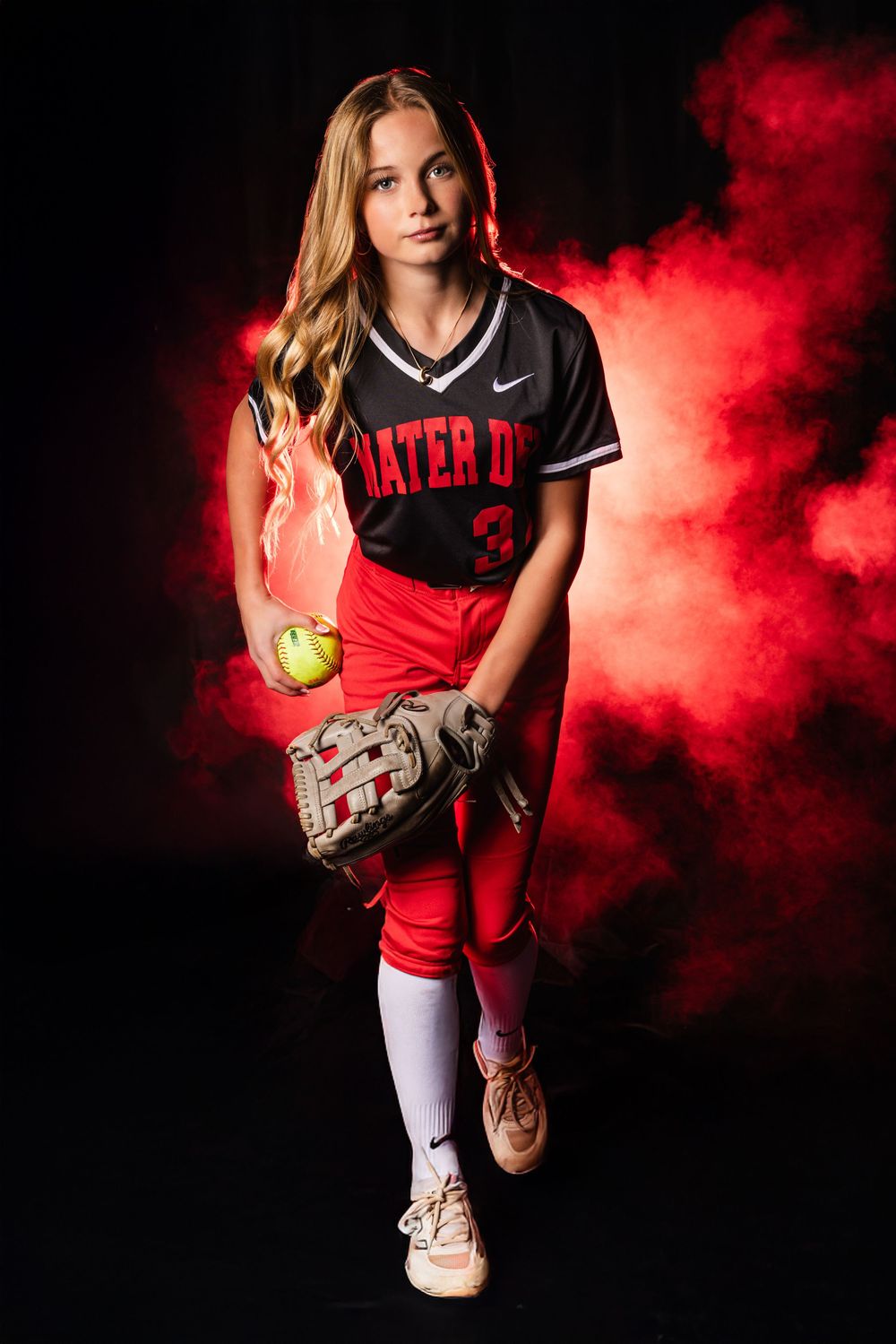 Dramatic softball photo series with red smoke effects showing player poses in black and red uniforms against dark background.