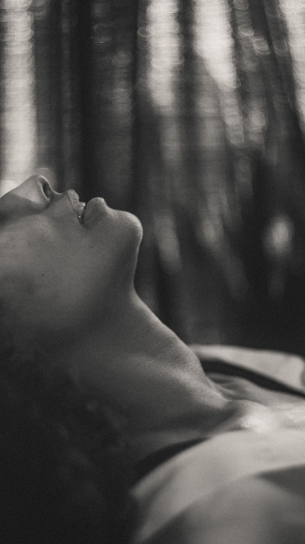Atmospheric black and white profile portrait with dreamy forest backdrop creating ethereal mood.
