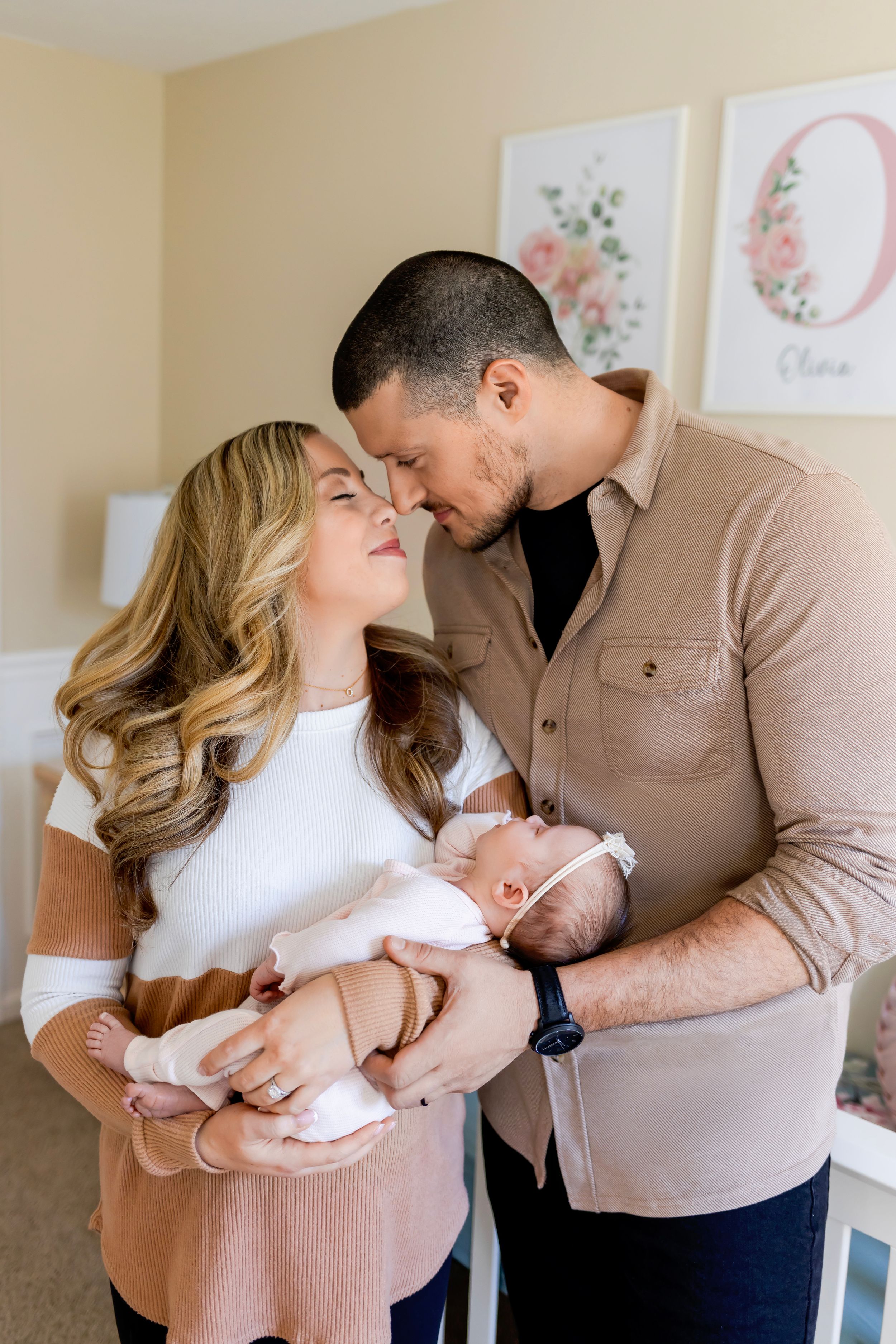 A couple shares an intimate moment while holding their newborn baby. NJ Newborn Photographer in home session.