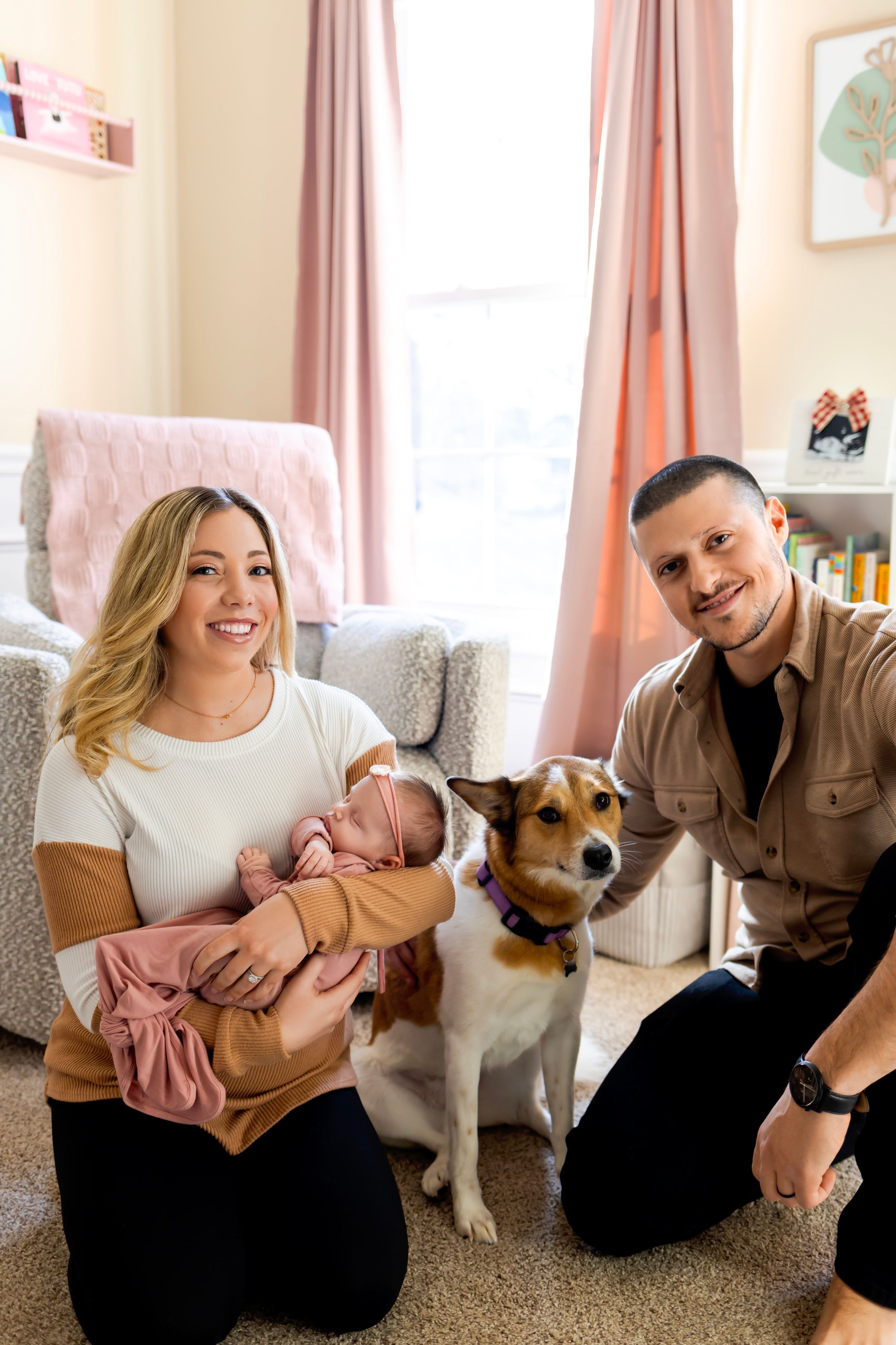 A family sits in a cozy living room with their Jack Russell terrier and newborn baby. Newborn Lifestyle Photographer in Sussex County NJ