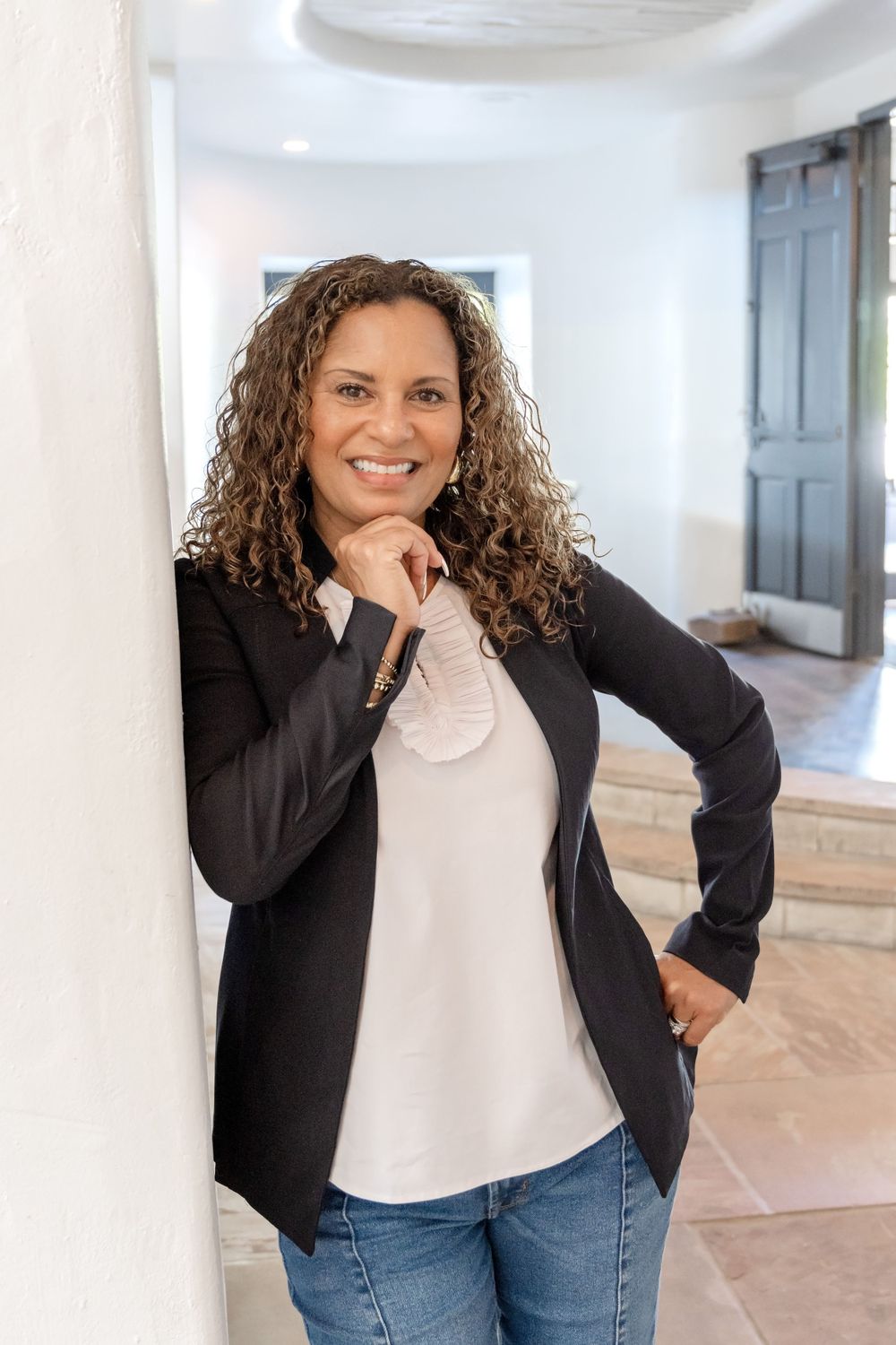 Professional portrait in business casual attire against white interior wall.