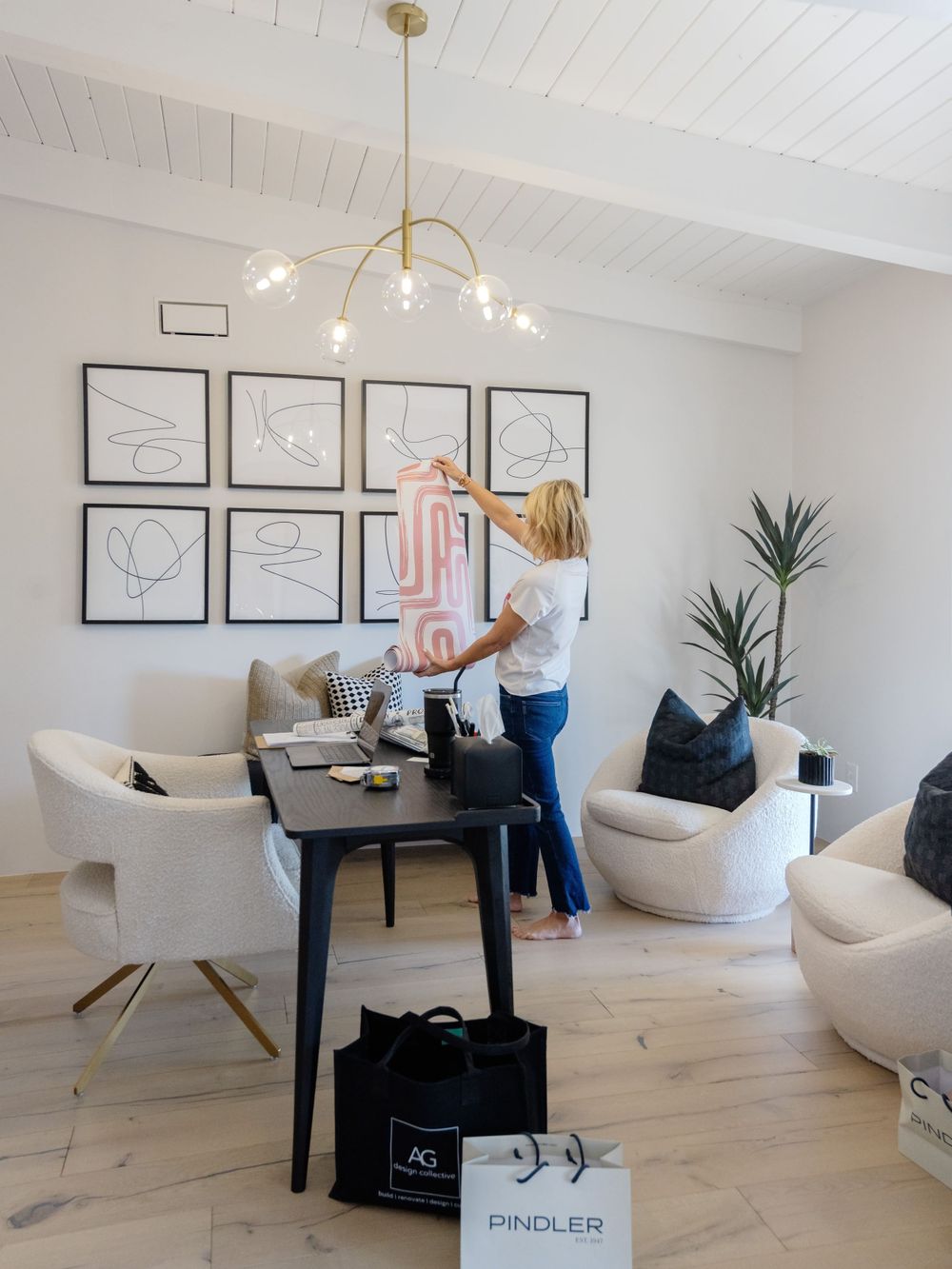 Modern interior with black and white artwork gallery wall and contemporary gold light fixture.