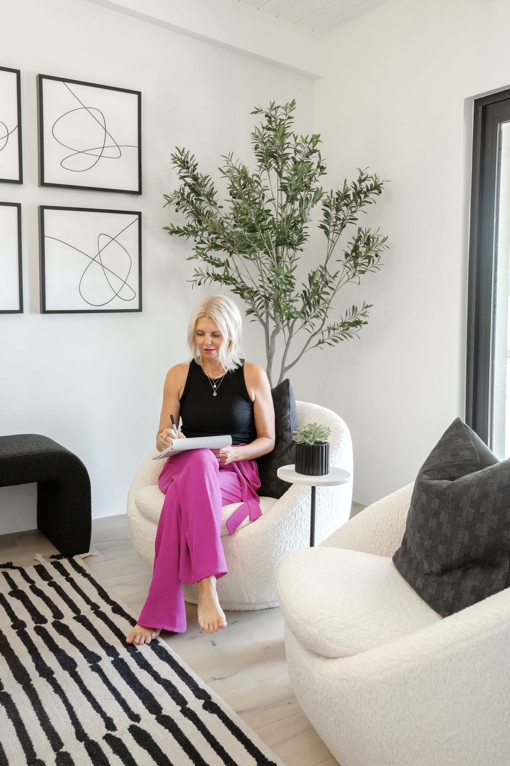 Contemporary living space with geometric wall art, indoor plant, and black and white striped rug.