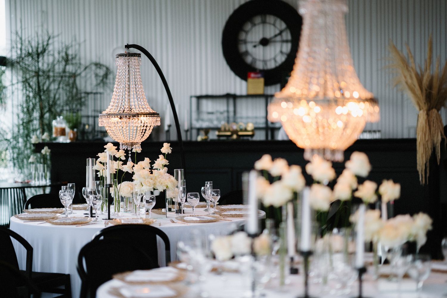 Elegant wedding reception tables set with crystal chandeliers and white floral centerpieces.