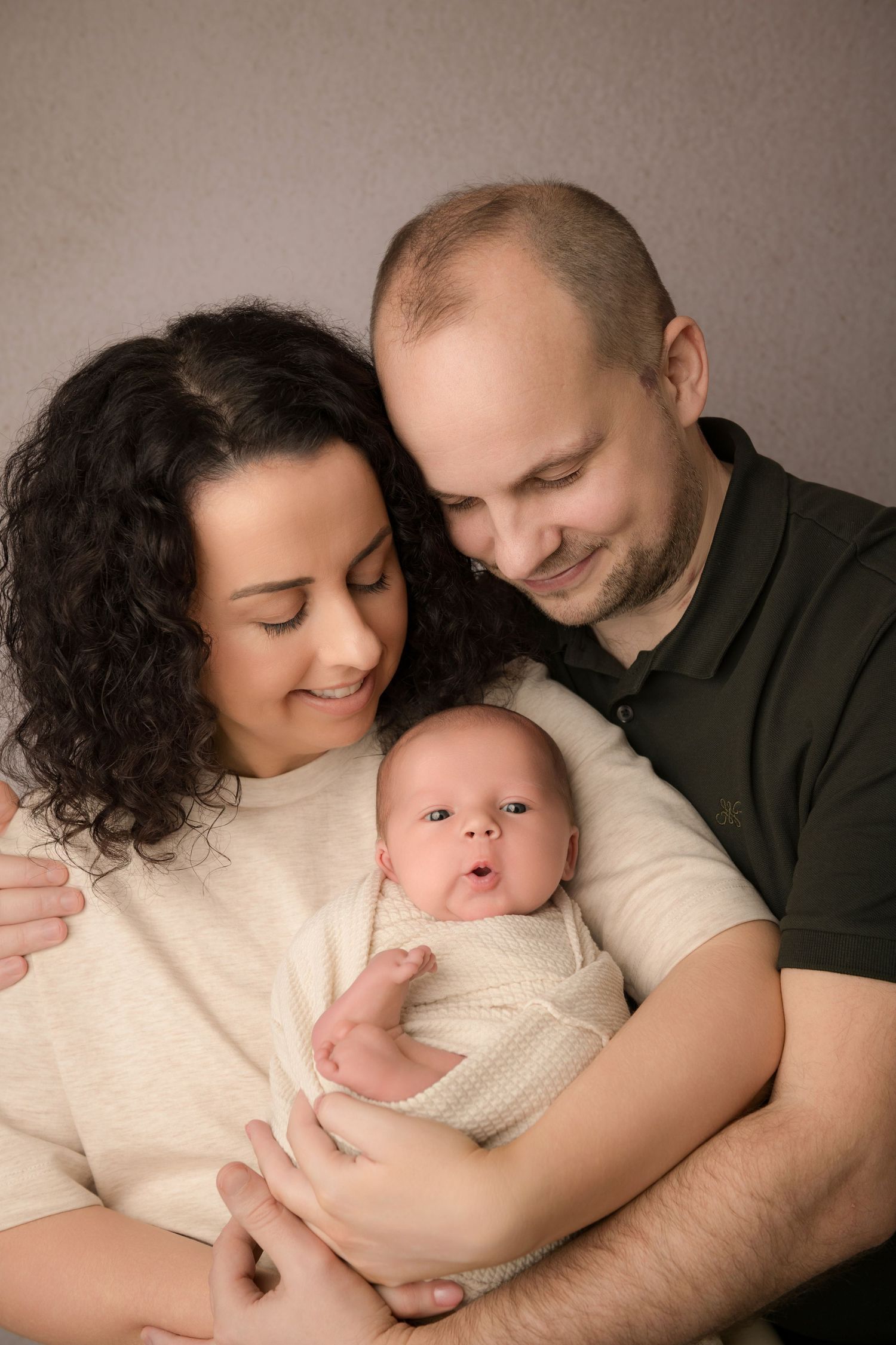 A series of intimate newborn photography portraits showing tender family moments with a baby in cream-colored outfits.