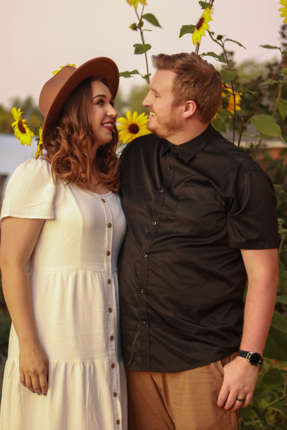 A couple shares a romantic moment among blooming sunflowers.