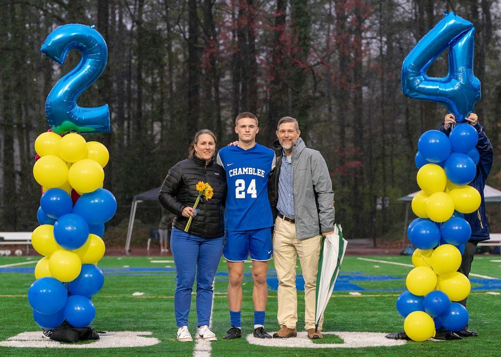 Athletic celebration setup with blue and yellow balloon columns showing numbers 2 and 4 on a field.
