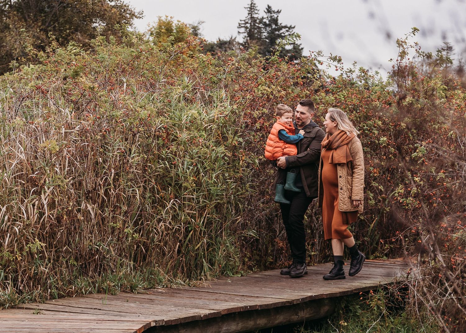 Couple sharing an intimate moment on a wooden boardwalk surrounded by fall foliage.