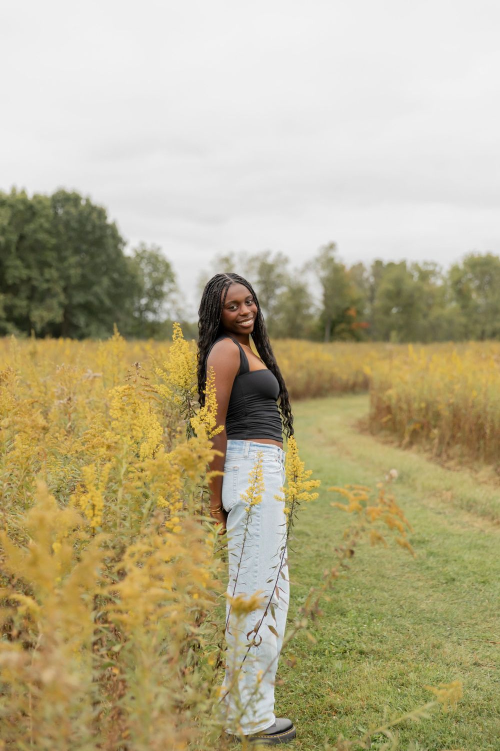 teenage girl standing in a field of flowers smiling for a photo