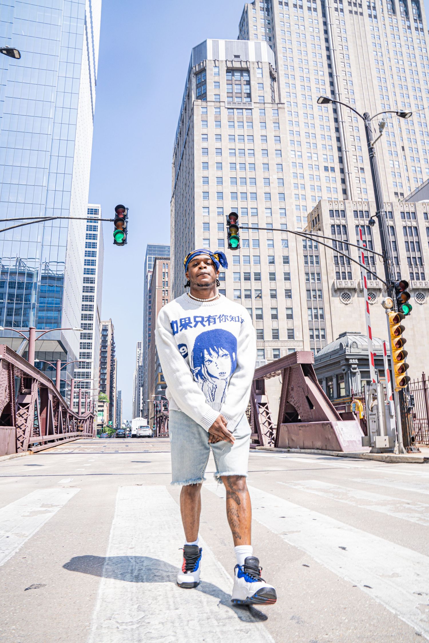 Street fashion photo on a Chicago bridge with tall buildings and traffic lights in the background.