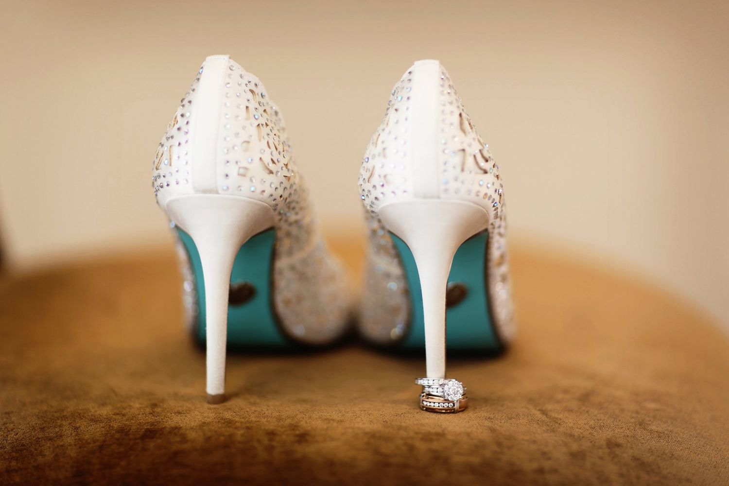 Elegant white lace wedding shoes with high heels photographed from behind.