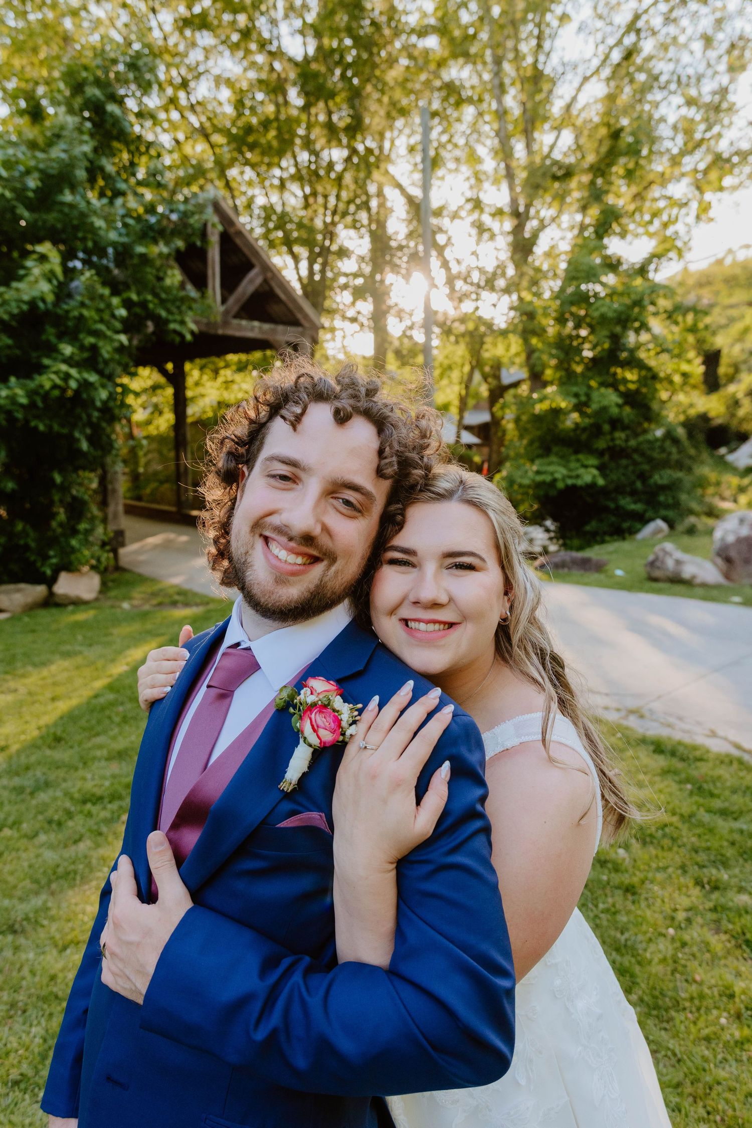 Wedding couple posing together outdoors with natural greenery backdrop.