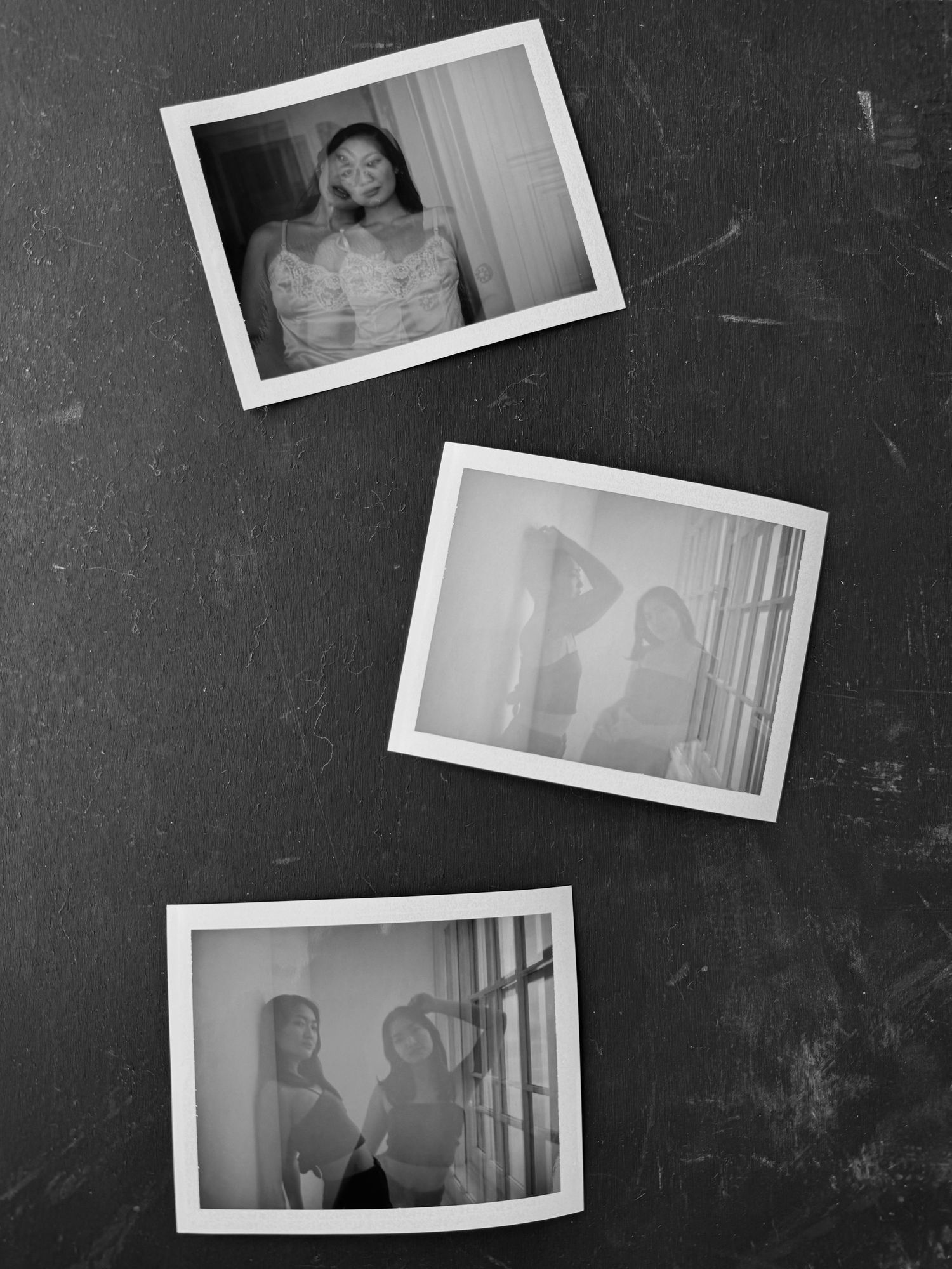 Three vintage black and white polaroid photographs arranged on a dark textured surface.