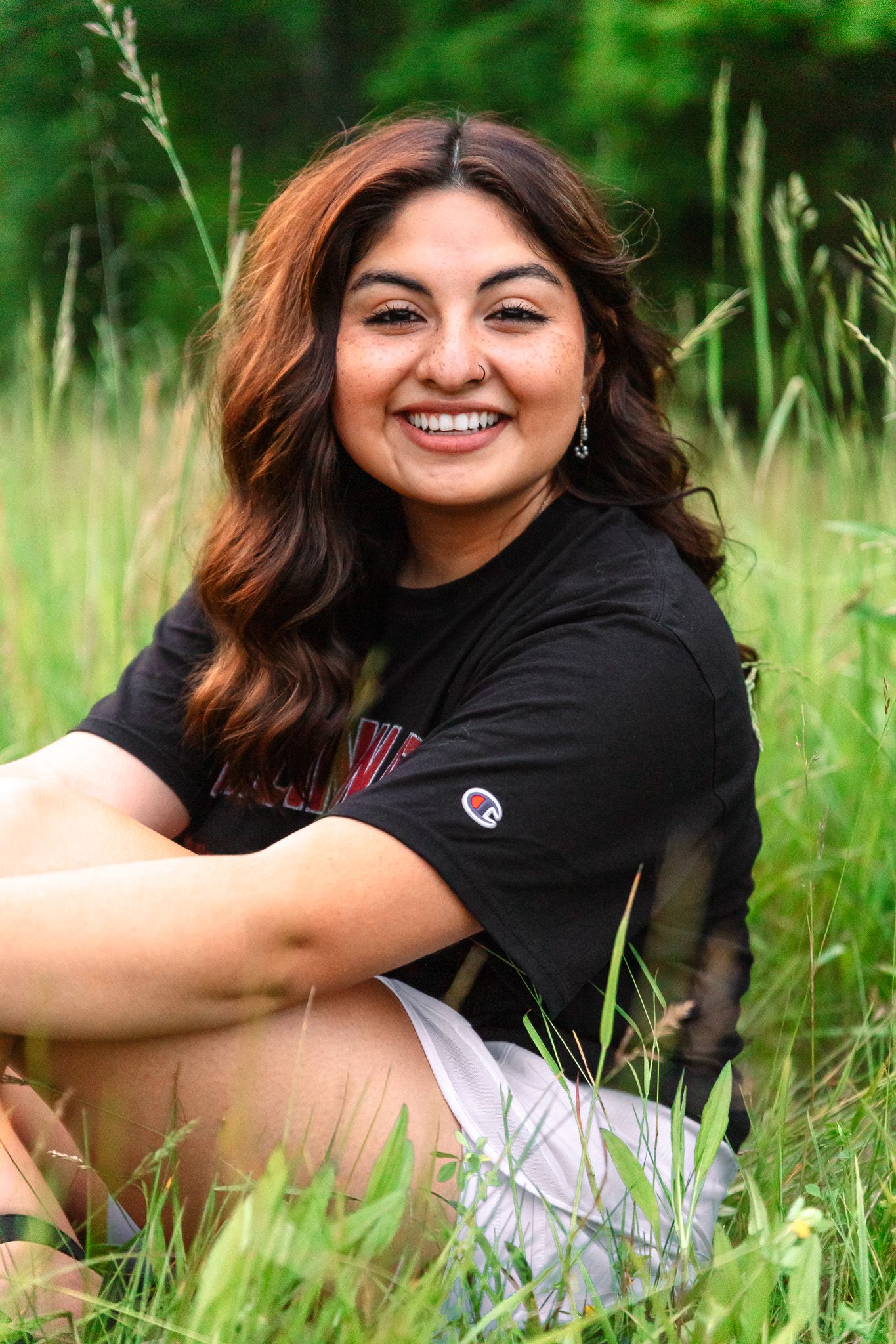 Senior portrait session in grass field with casual black t-shirt and natural lighting.