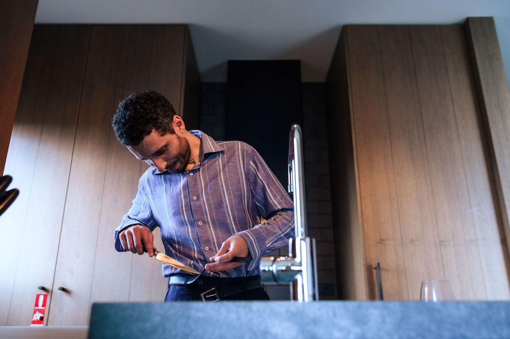 Person in striped button-down shirt working behind modern kitchen counter.