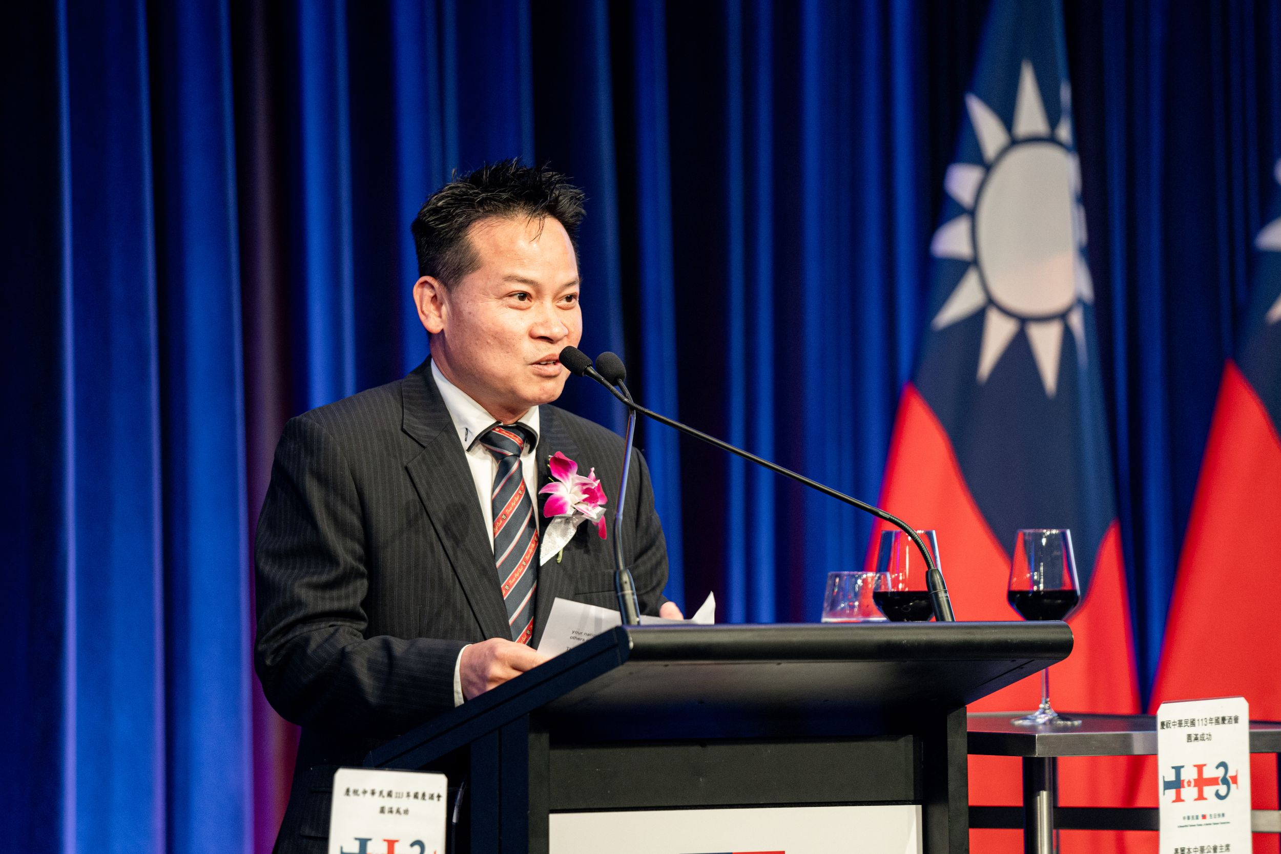 Speaker at podium with Taiwan flag backdrop during official ceremony.