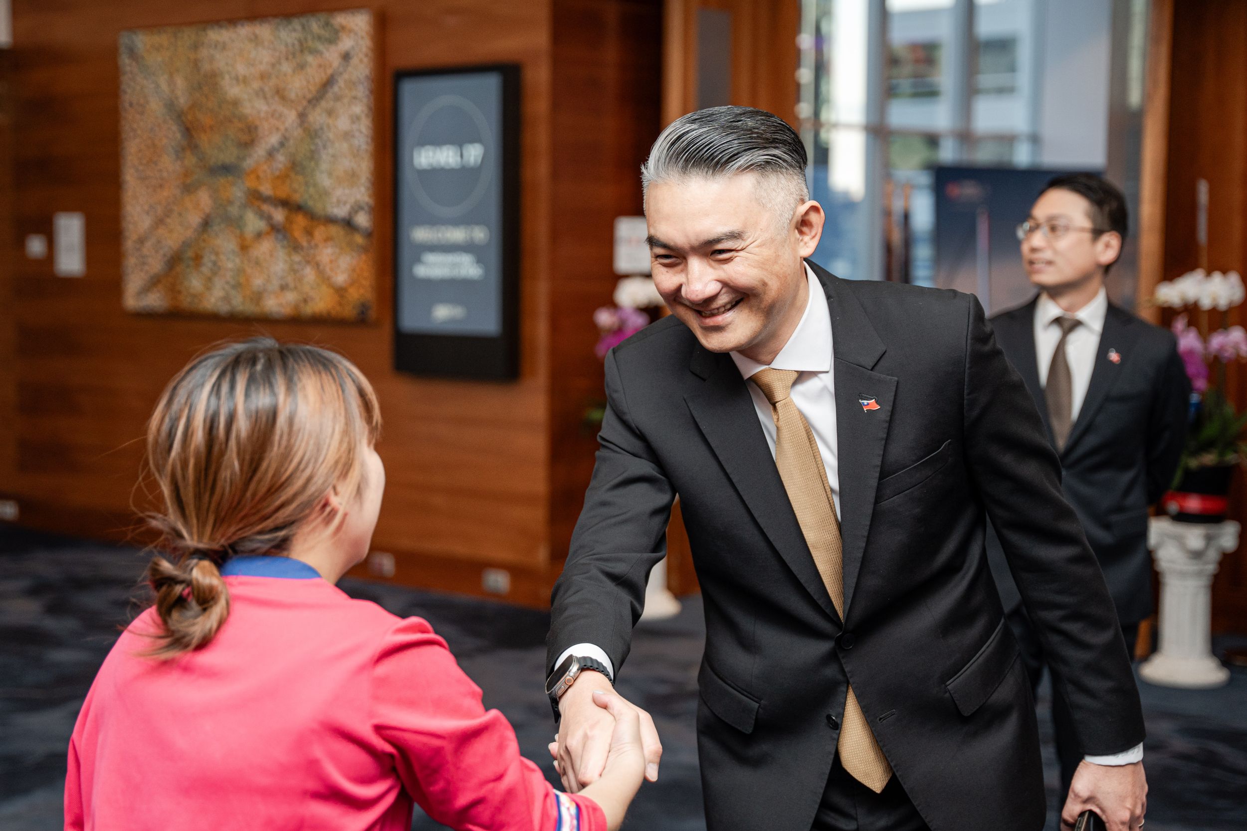 A warm business greeting exchanged between professionals at an office entrance.